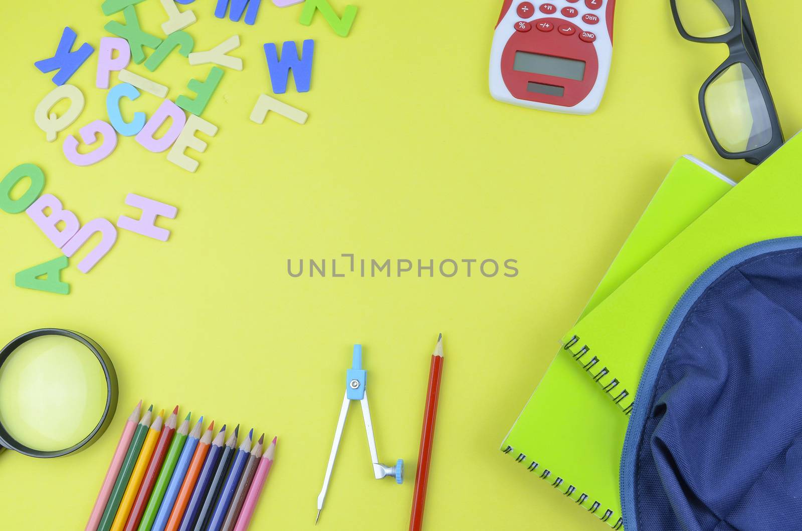 Student backpack and various school supplies. Studying, education and back to school concept. Yellow background and selective focus.