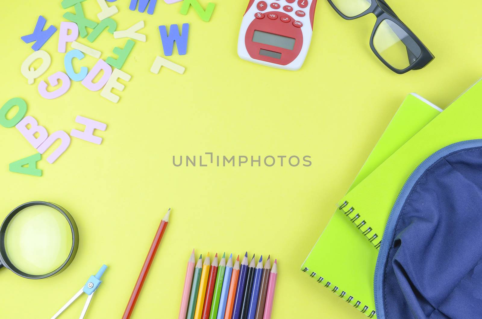 Student backpack and various school supplies. Studying, education and back to school concept. Yellow background and selective focus.