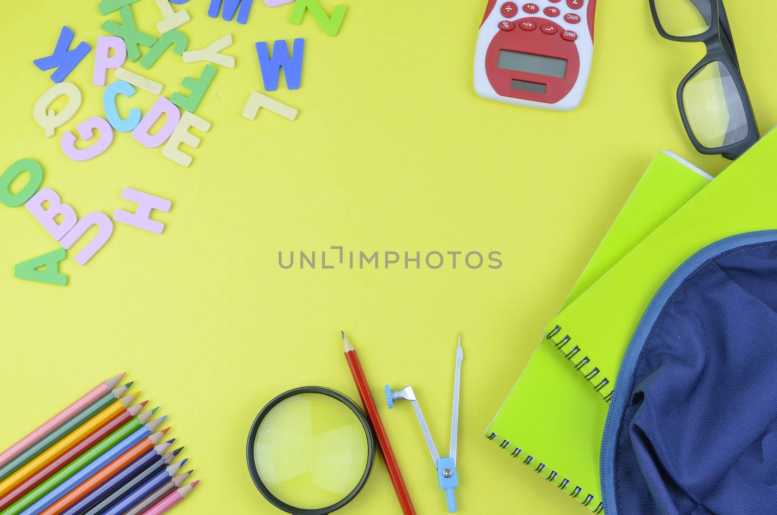 Student backpack and various school supplies. Studying, education and back to school concept. Yellow background and selective focus.