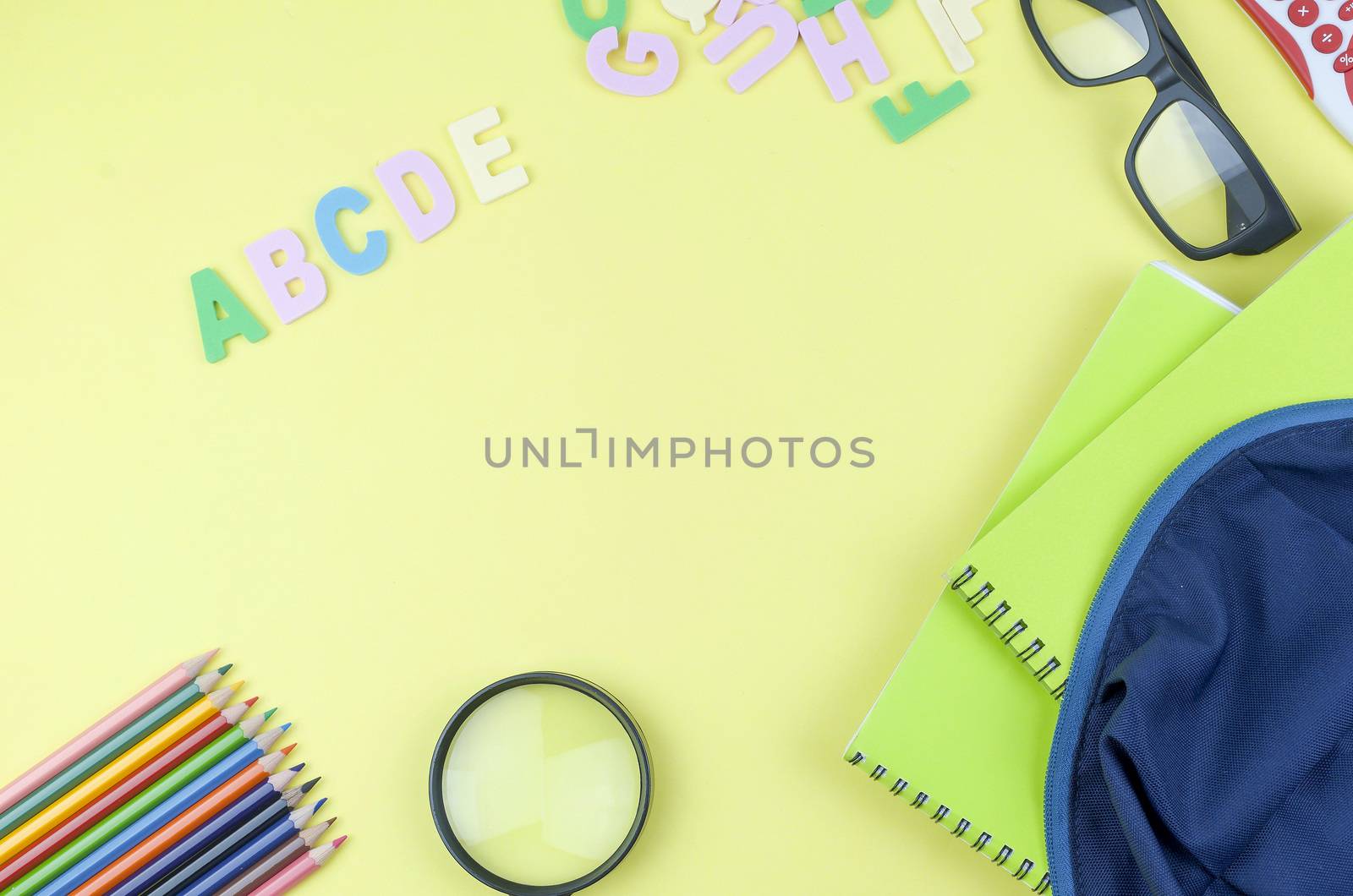 Student backpack and various school supplies. Studying, education and back to school concept. Yellow background and selective focus.