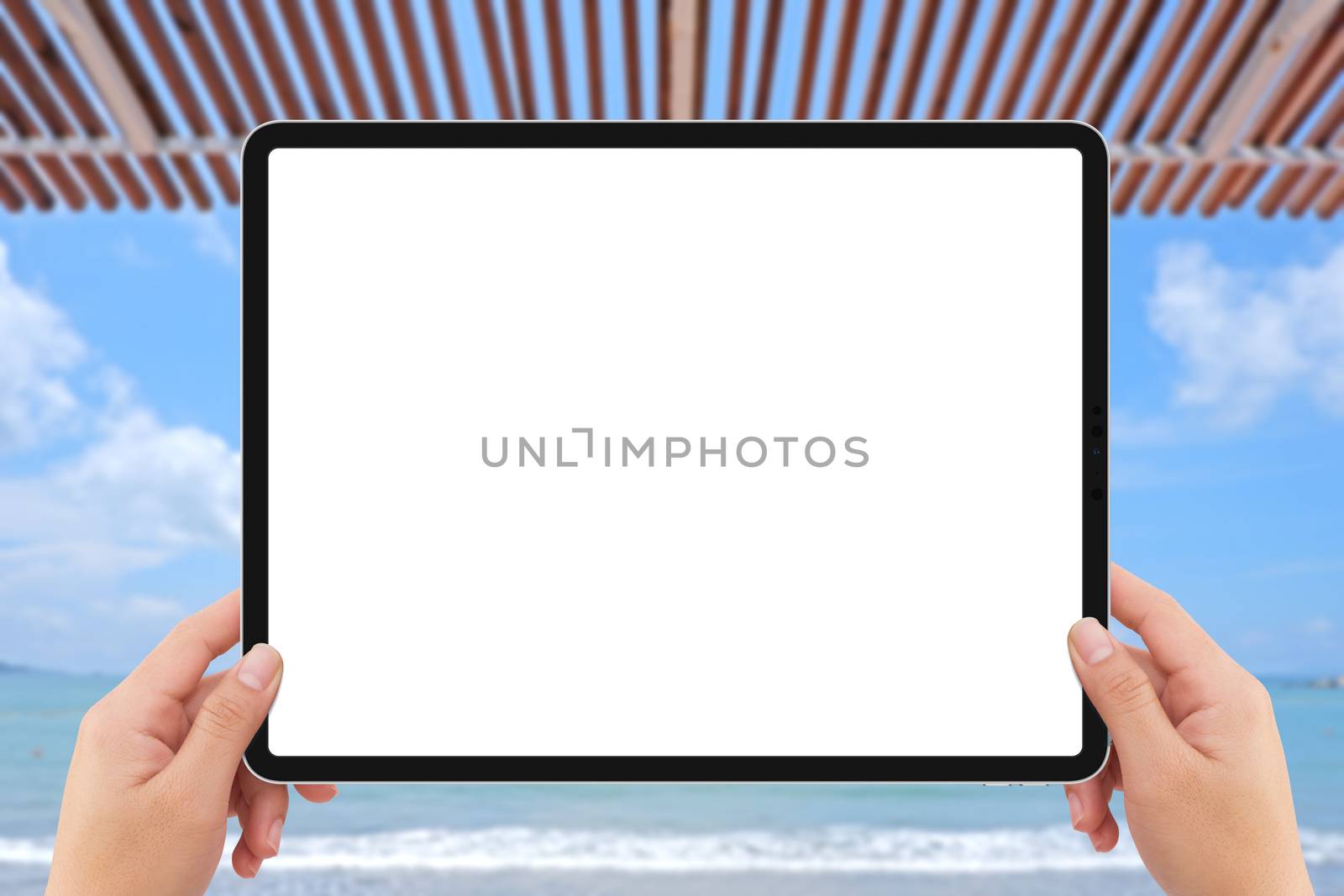 The human two hands holding white tablet computer white screen mockup near beach