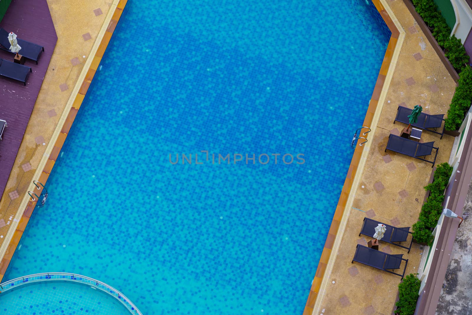 Top view swimming pool at the edge of the pool is wood. Stick with the pool stairs. In the summer and clean water is blue deep and shallow  for children and adults. Stick with the pool stairs. background.