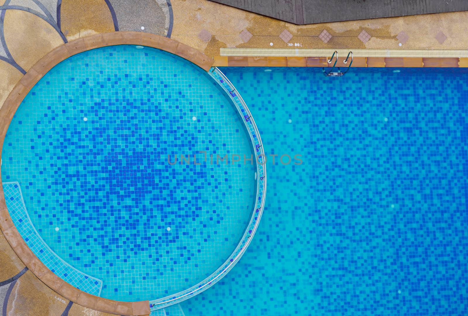 Top view swimming pool at the edge of the pool is wood. Stick with the pool stairs. In the summer and clean water is blue deep and shallow  for children and adults. Stick with the pool stairs. background.