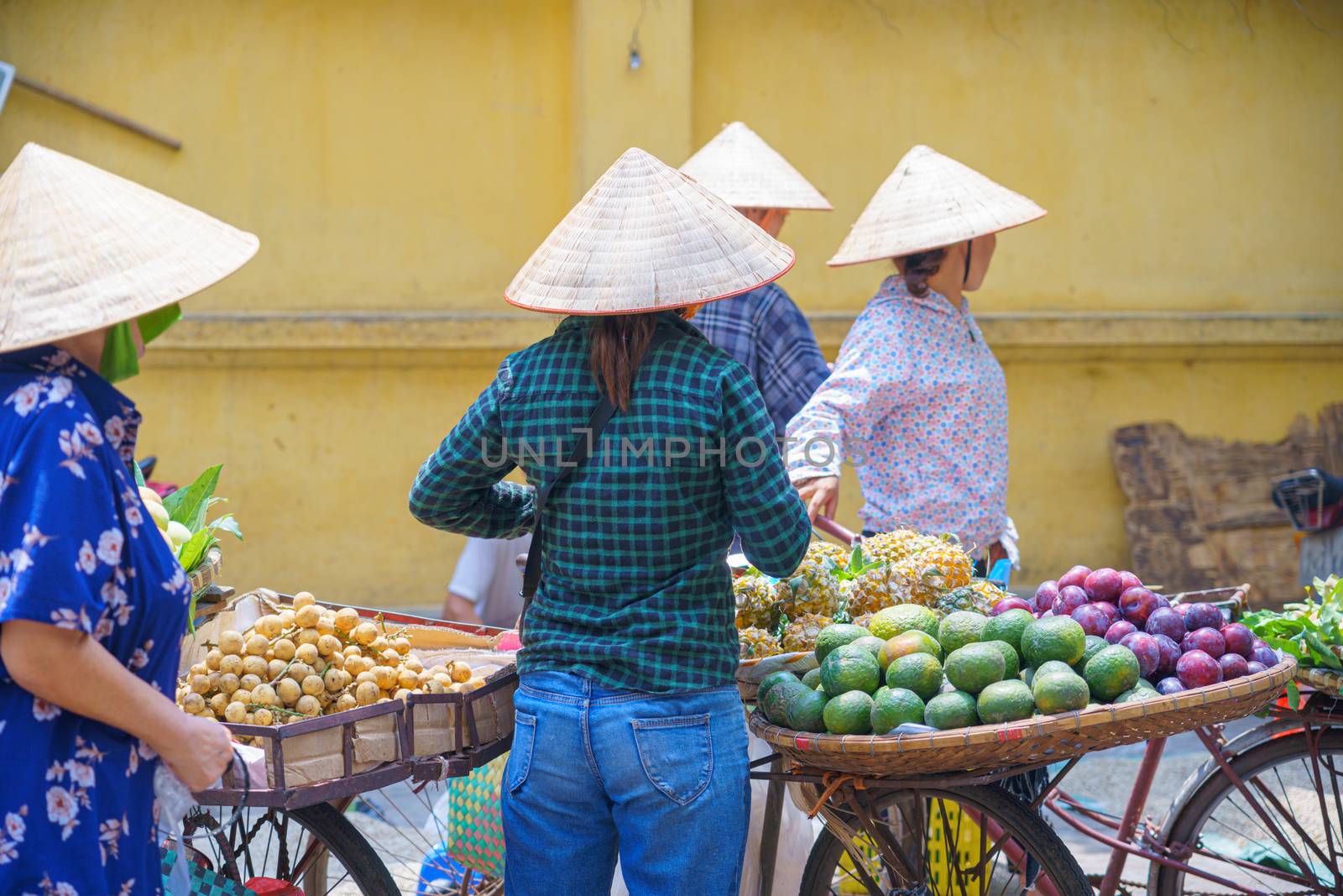 Back view of Women, Female street vendor in fruit, flowers market on the bike and street in VIETNAM HANOI
