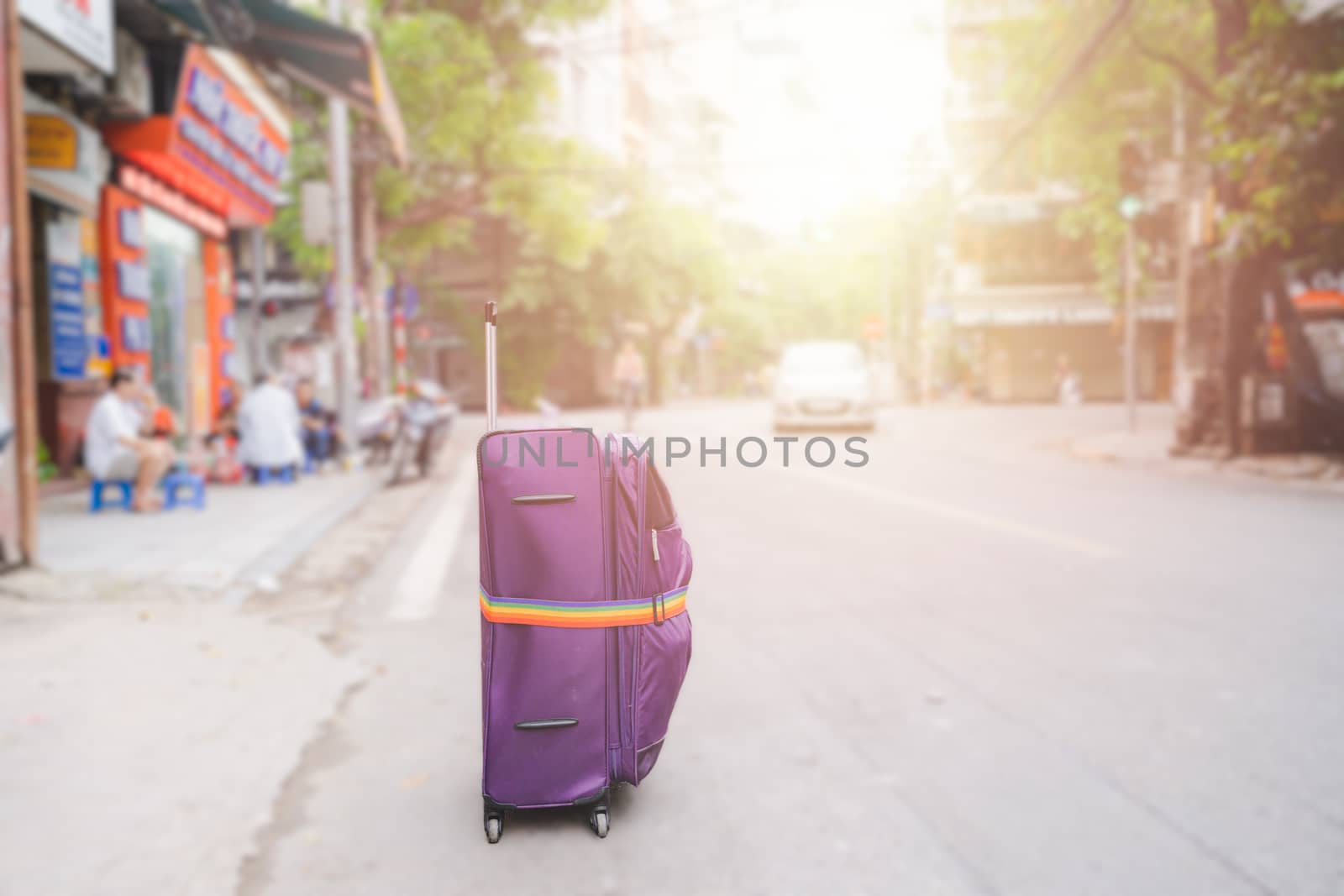 Purple Luggage strap or suitcase on the streets rood of big cities when traveling backpacker on vacation day  in HANOI VIETNAM sunlight, flare,  beautiful trees and blur background concept.