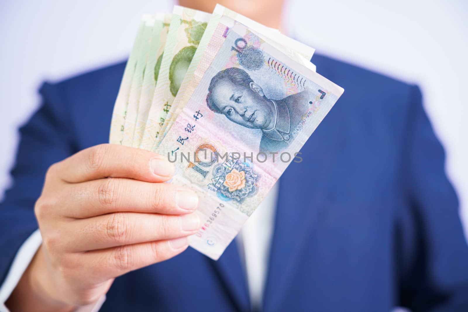 Money in China hold on hand business man wearing a blue suit CNY, Pay, exchange money People’s Republic of China (PRC) on white background.