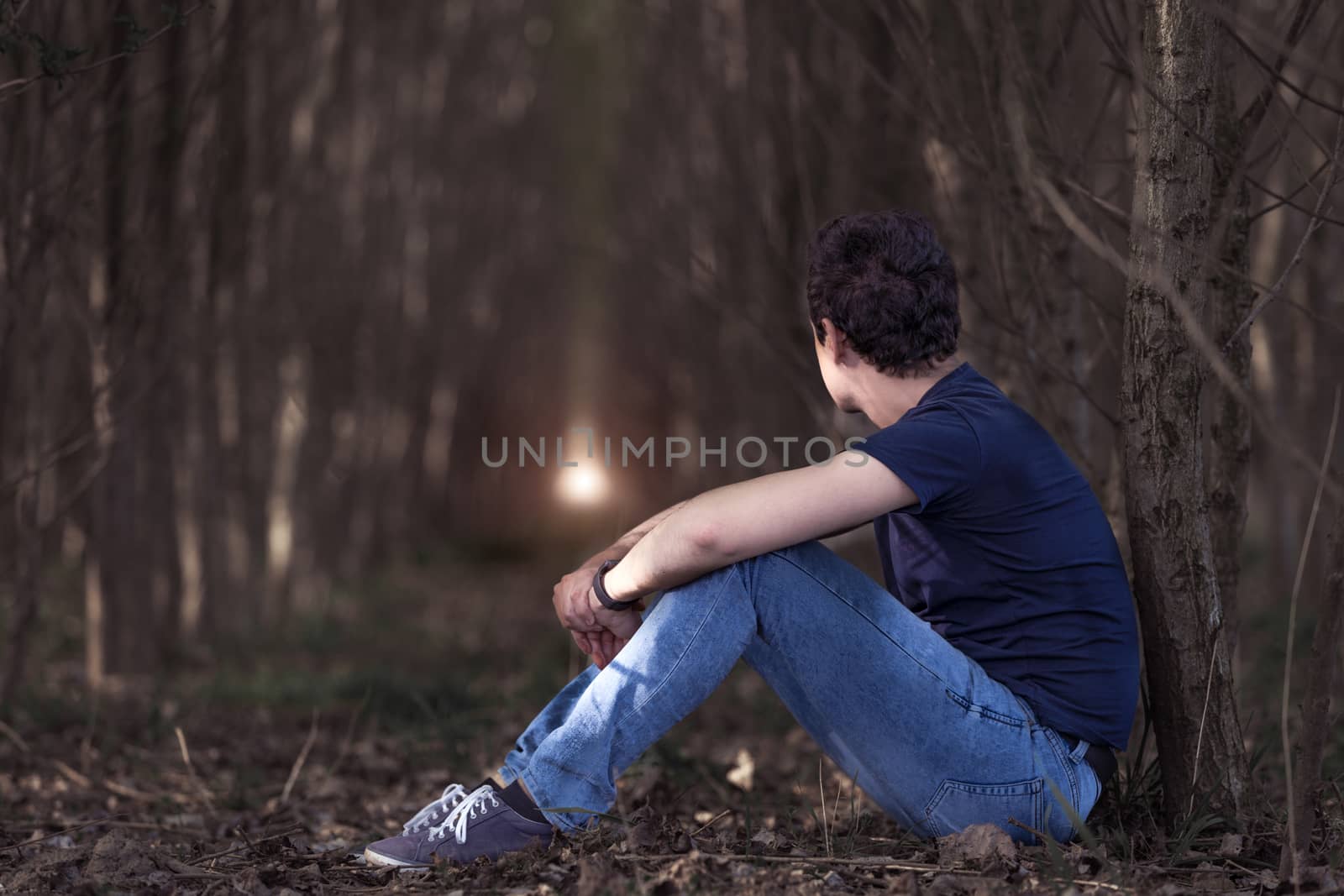 A thoughtful man in the woods looks up to the light in the hope of better times. copy space by Edophoto