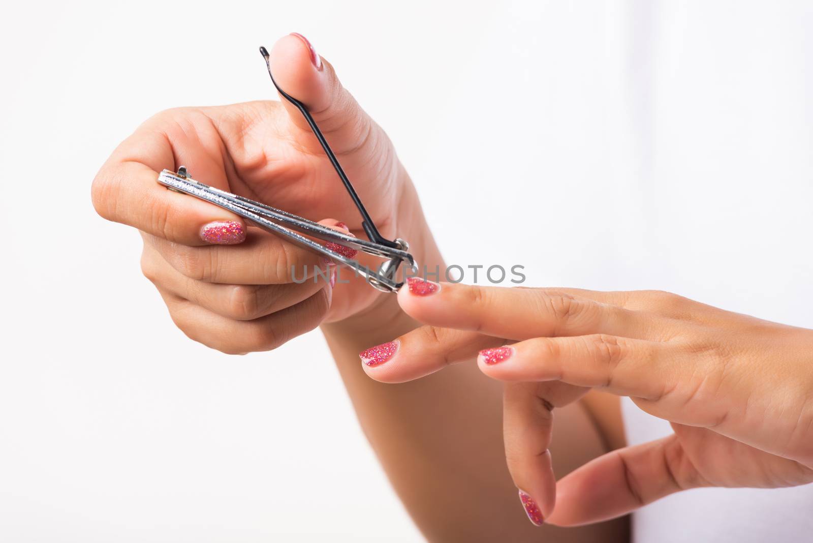 Woman cutting nails on finger using a nail clipper by Sorapop