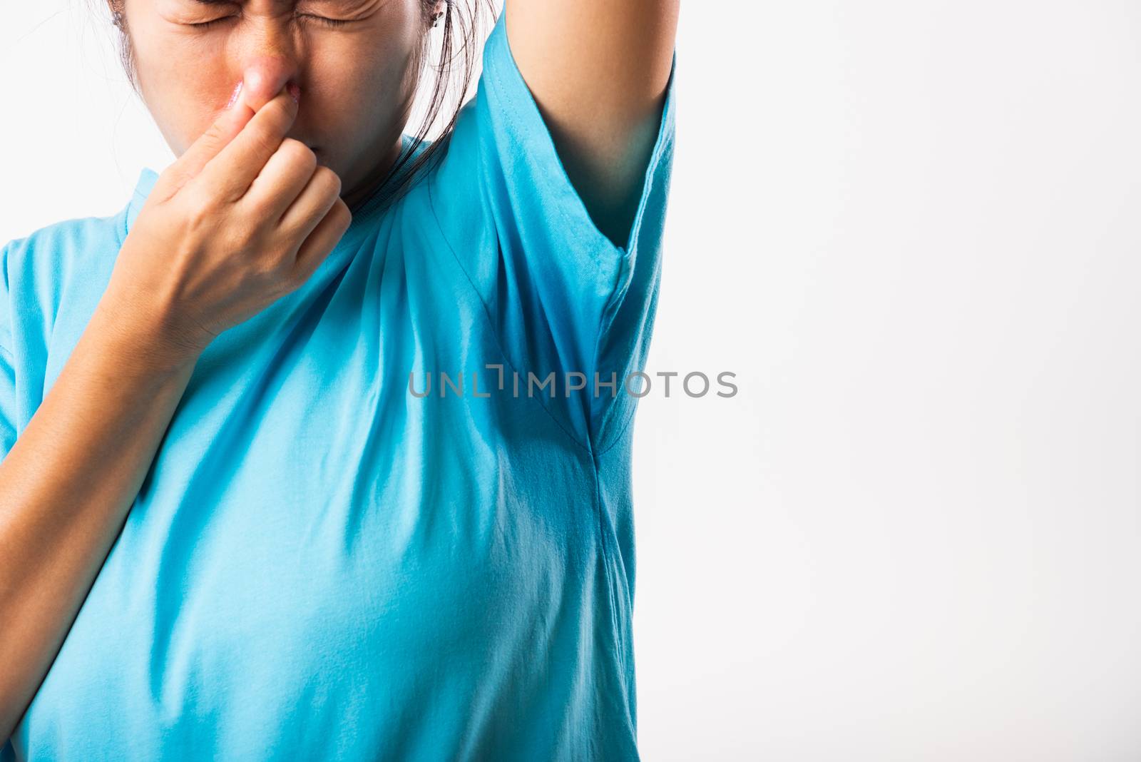 Closeup young Asian young woman hyperhidrosis sweating. Female have armpit sweat stain on her clothes smelly use hand close nose, studio shot isolated on white background, Healthcare medical concept