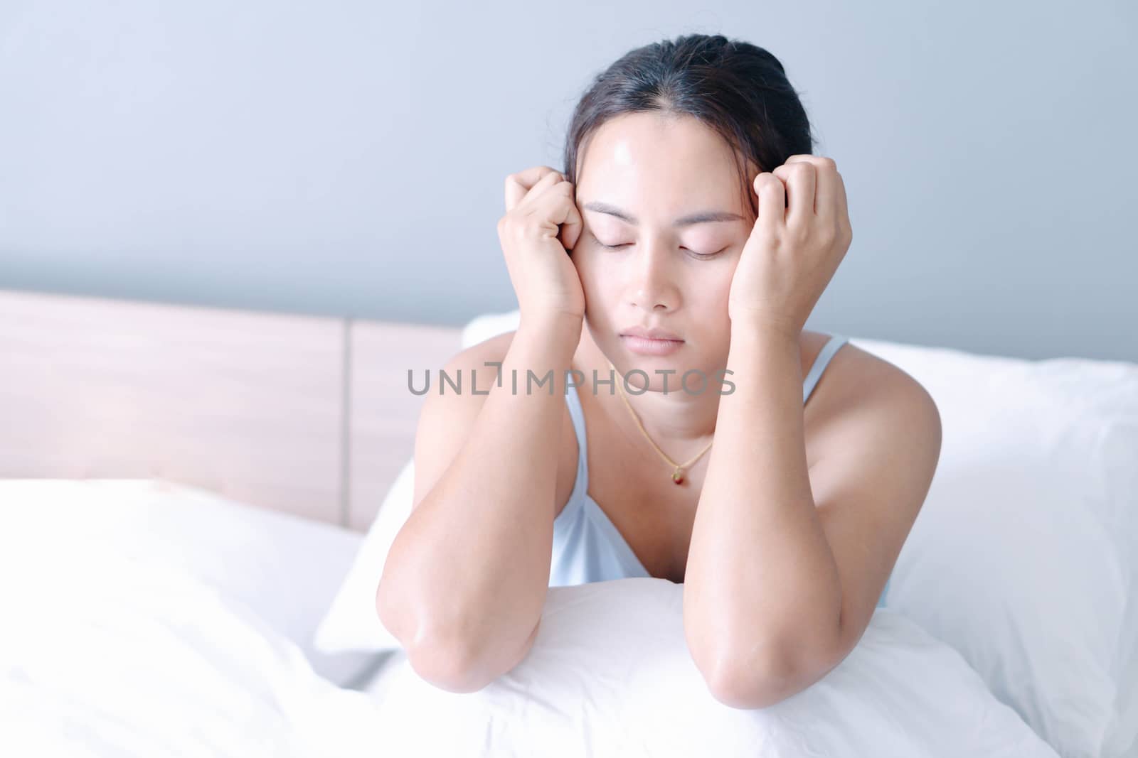 Closeup woman sitting on bed in the bedroom with thinking or depressed feeling, selective focus