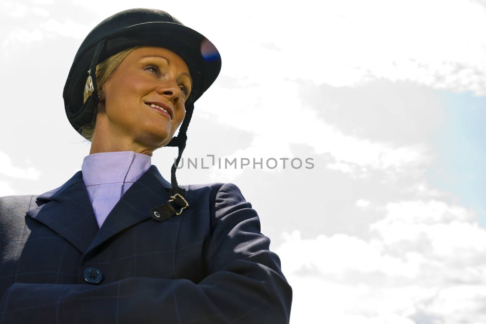 A blonde equestrian model poses outdoors before a horse show