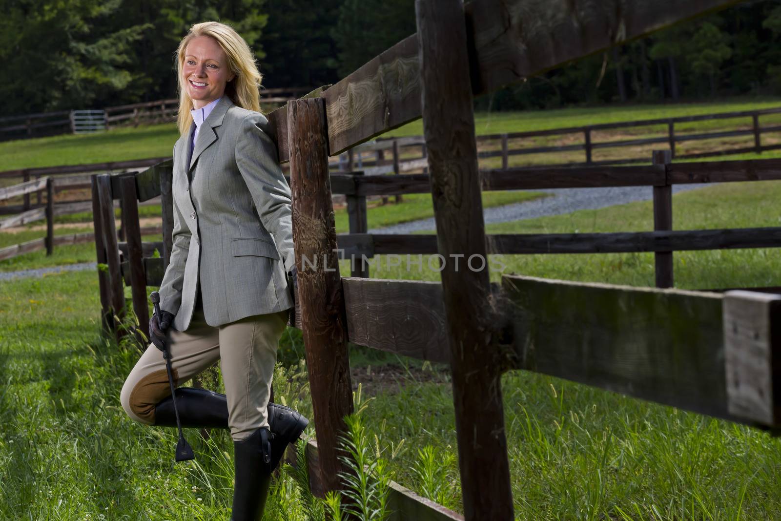 A blonde equestrian model poses outdoors before a horse show
