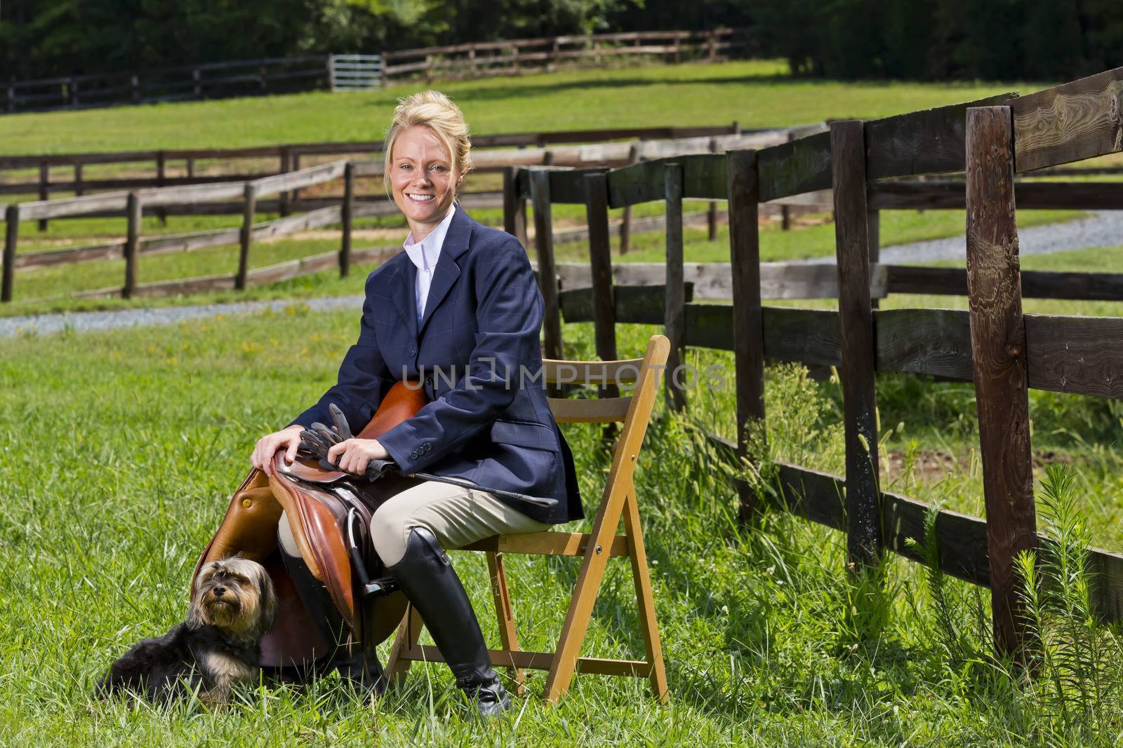 A blonde equestrian model poses outdoors before a horse show