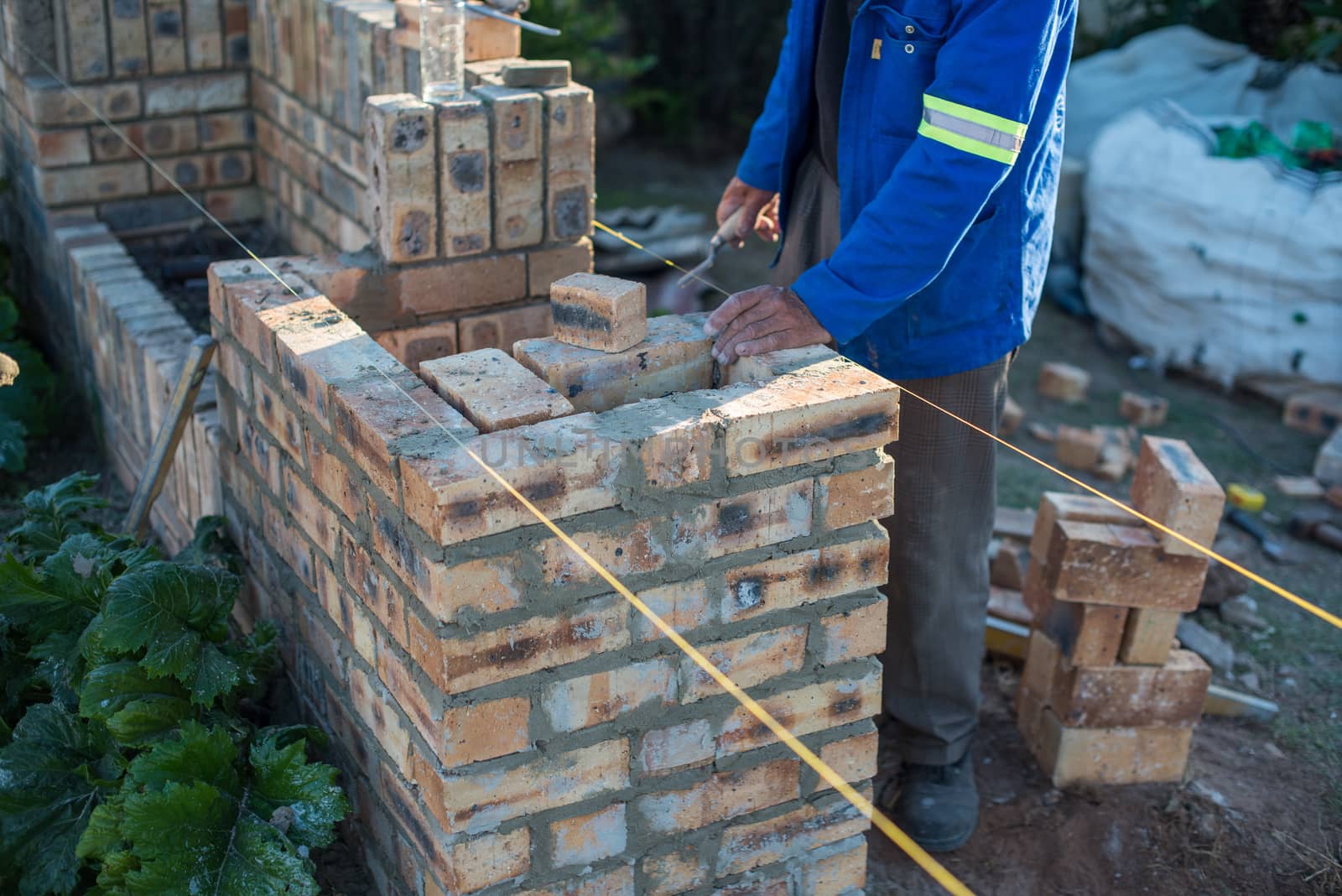 Worker laying bricks for wall shot from side angle