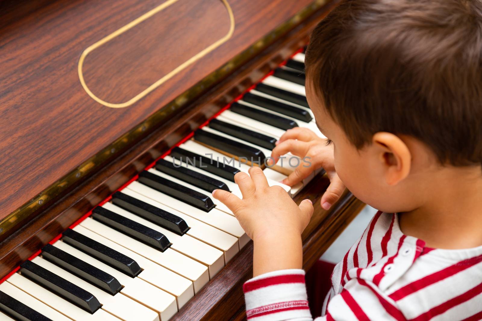 Litlle boy playing the piano, toddler learning music at home