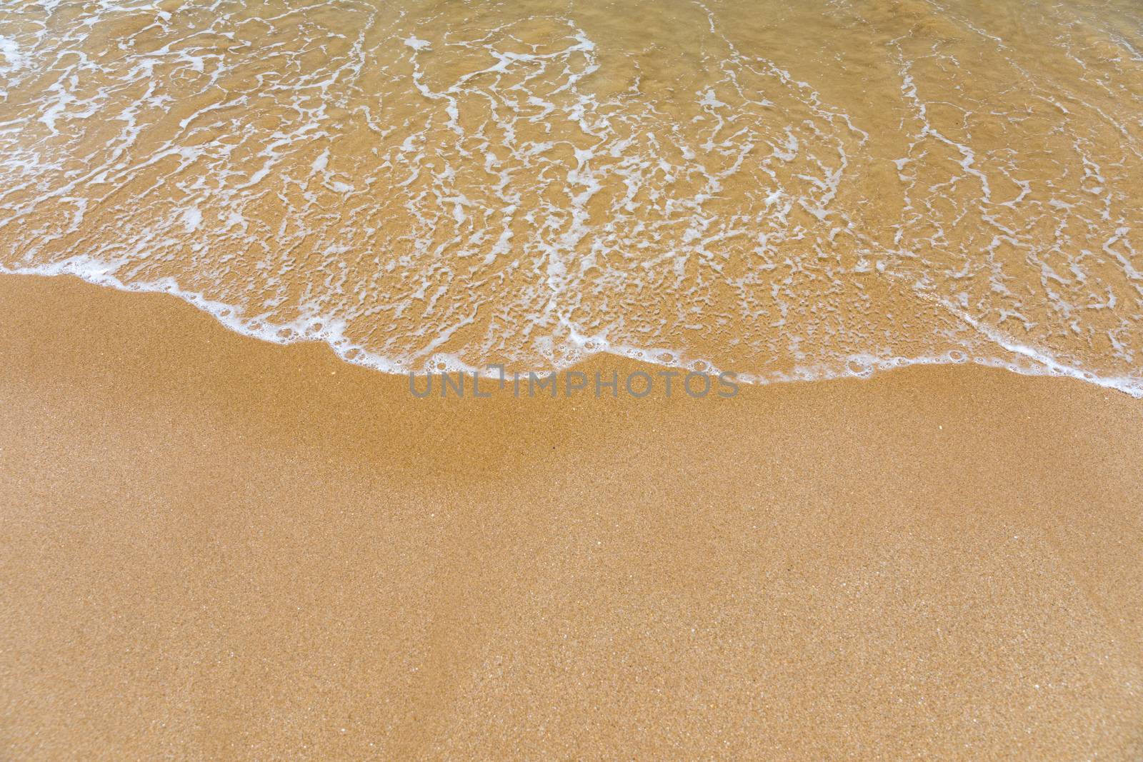 Blue ocean wave on sandy beach. Soft wave of blue ocean on sandy beach. Background. Top view of Beautiful beach with tranquil wave, sea and ocean background, summer vacation concept. 