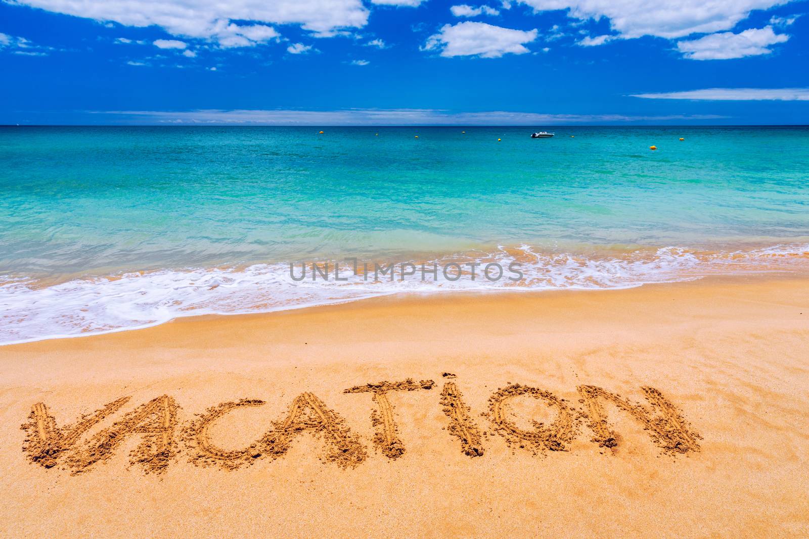 Vacation text on a beach. Vacation written in a sandy tropical beach. "Vacation" written in the sand on the beach blue waves in the background. Vacation on the sand beach concept.