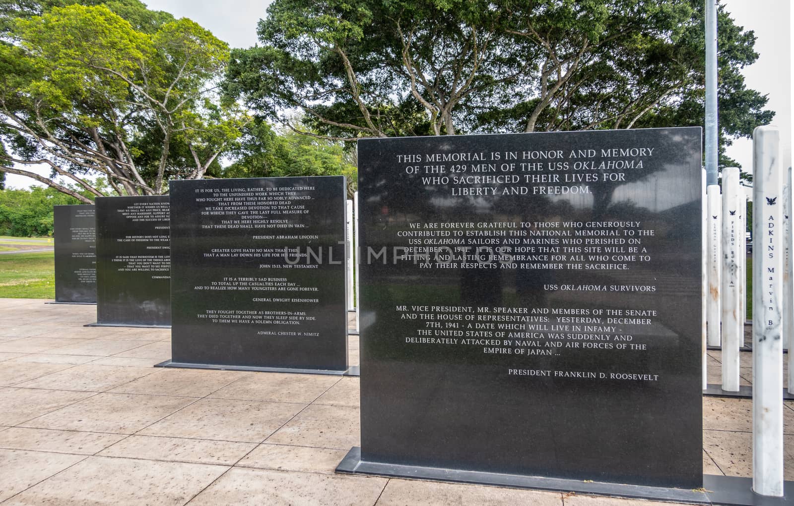 Oahu, Hawaii, USA. - January 10, 2020: Pearl Harbor, Line of black steles, marble slabs with texts at USS Oklahoma memorial. Green foliage in back.