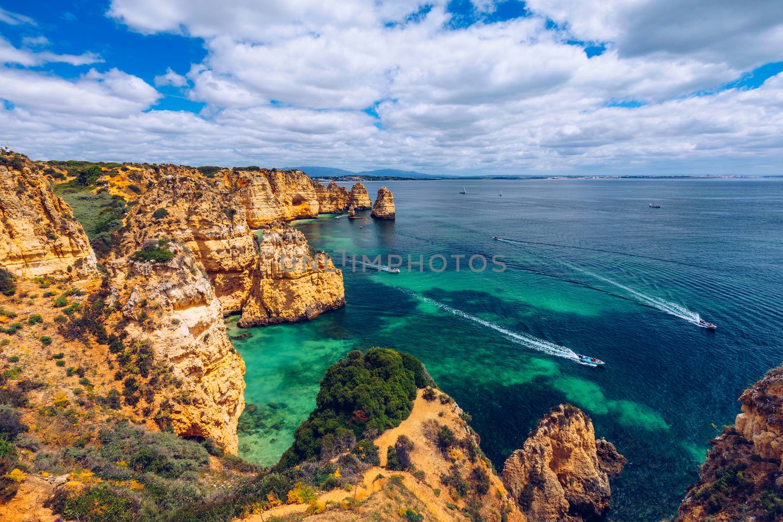 Panoramic view, Ponta da Piedade near Lagos in Algarve, Portugal. Cliff rocks and tourist boat on sea at Ponta da Piedade, Algarve region, Portugal. Ponta da Piedade, Algarve region, Portugal.