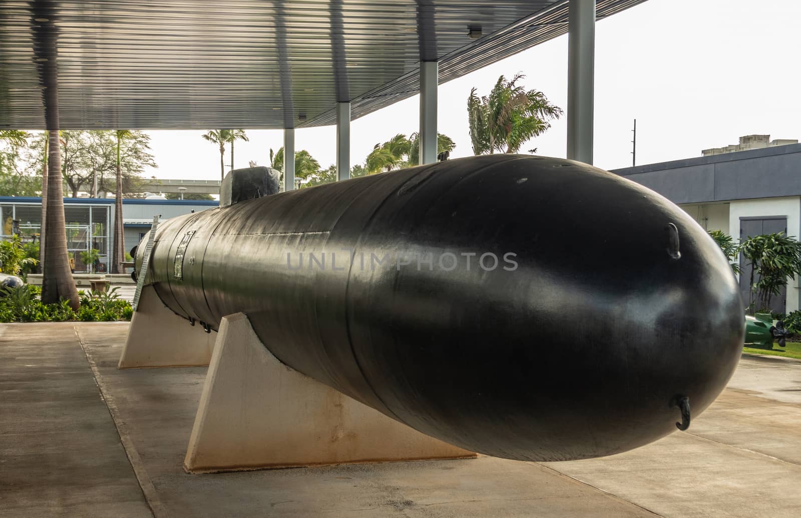 Oahu, Hawaii, USA. - January 10, 2020: Pearl Harbor. Big black One-man Japanese suicide or Kamikaze torpedo, called Kaiten, under gray metal roof. Green foliage in back.