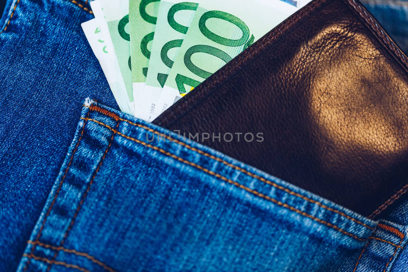 Brown wallet with euro money in the blue jeans pocket. Wallet with Euro banknotes. Cash in the wallet in the blue jeans pocket. Euro money in leather wallet.