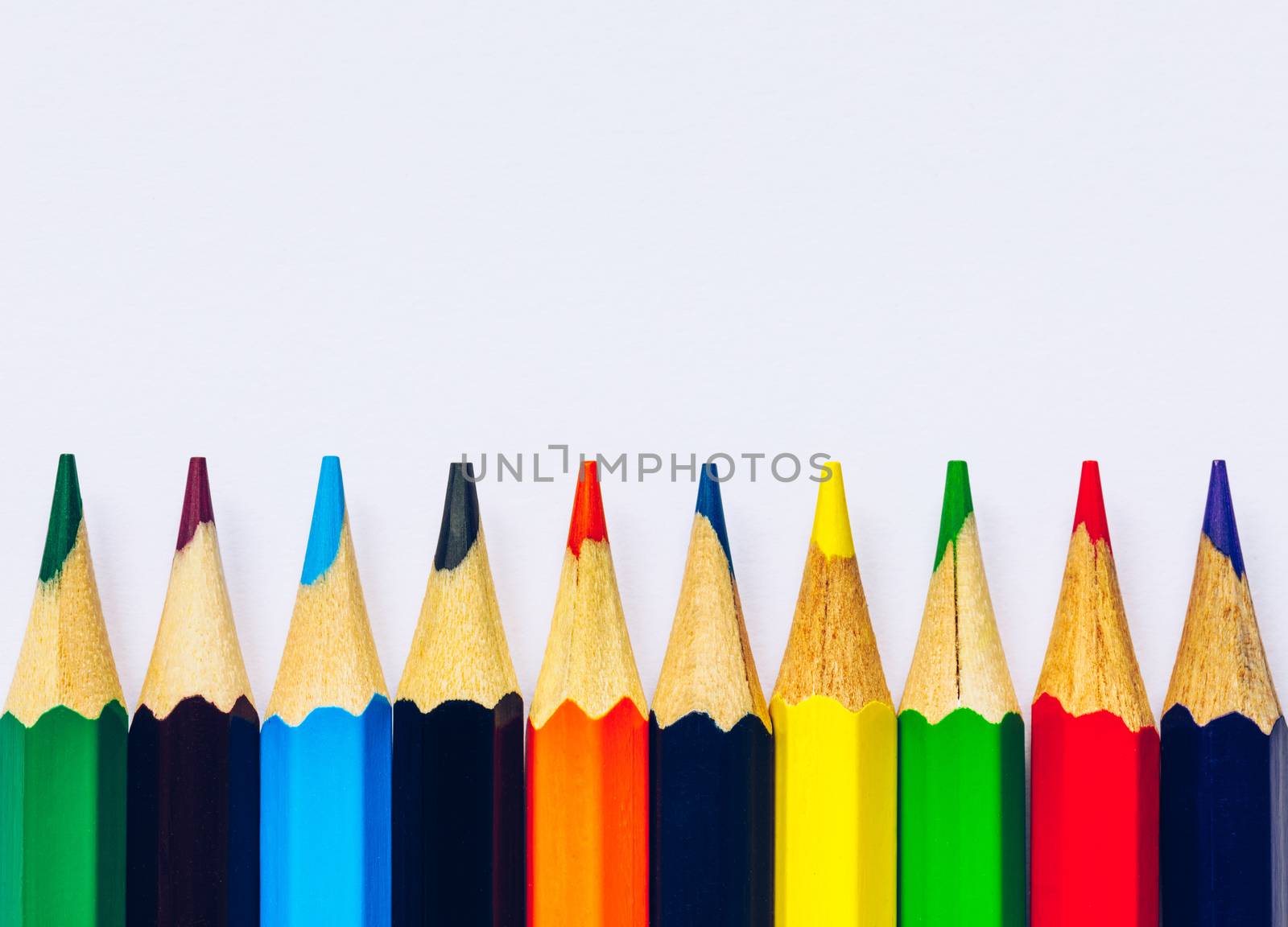 Color pencils isolated on white background. Close up of colored rainbow pencils for drawing, concept of preparing for school and discounts on stationery before the school year.