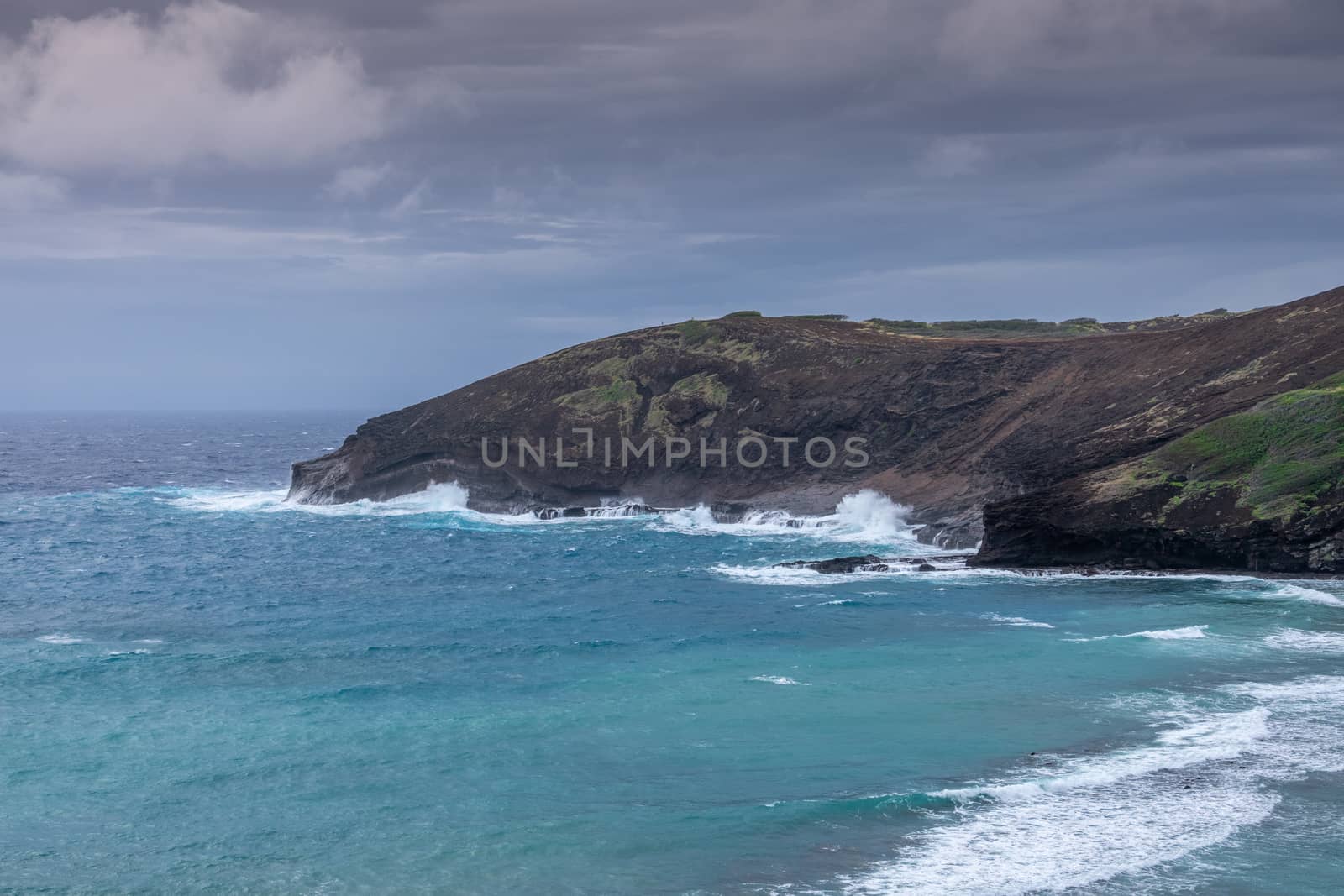 Waves run along cliffs at Hanauma Bay under storm clouds,  Oahu, by Claudine