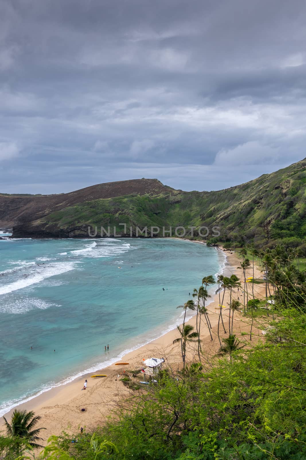 People on Beach of Hanauma Bay under storm clouds,  Oahu, Hawaii by Claudine