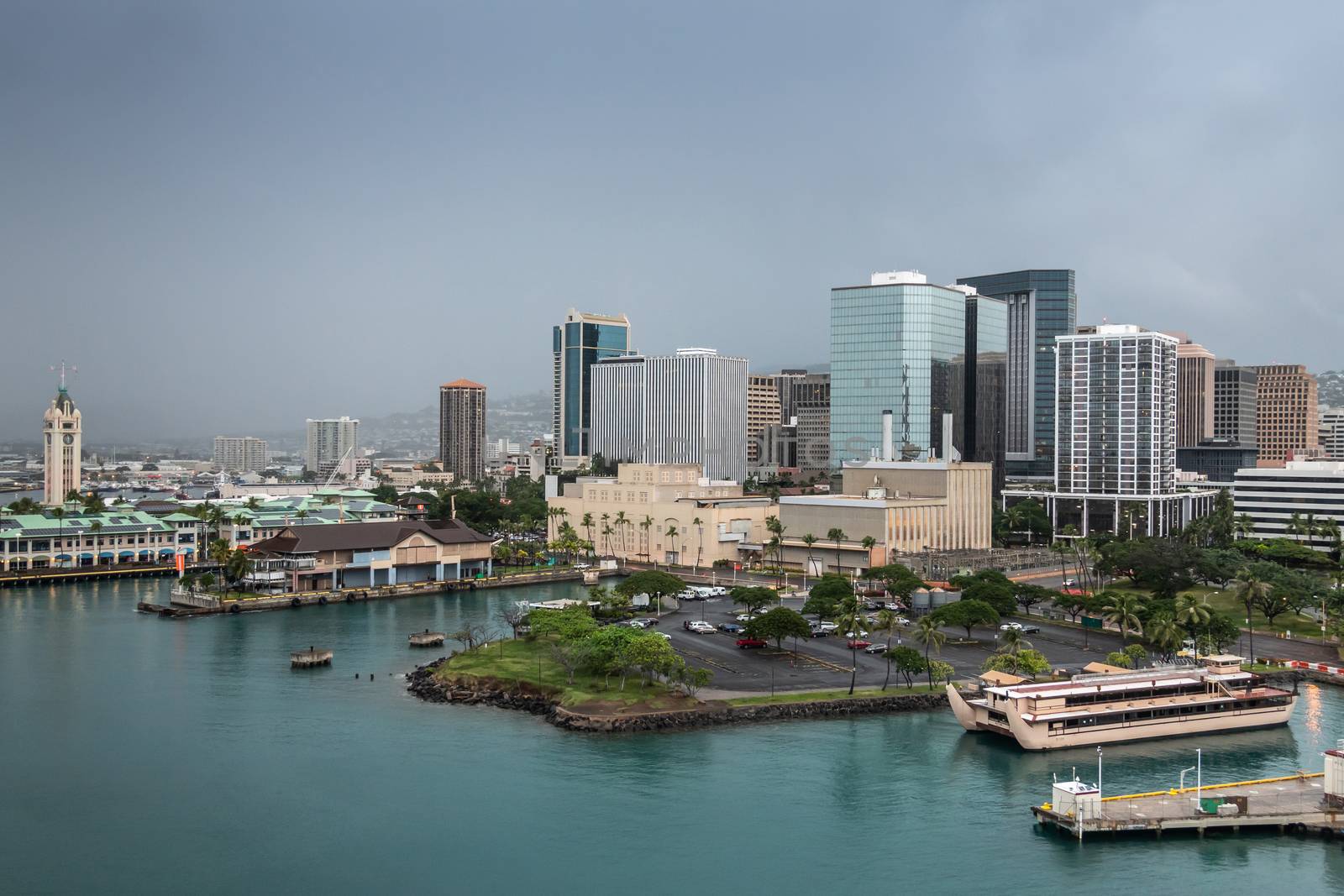 Honolulu  Oahu, Hawaii, USA. - January 11, 2020: Aloha Tower drive with pier 5 to 8 showing high rise buildings, the tower and its shopping mall, parking lots and more under dark rainy sky.