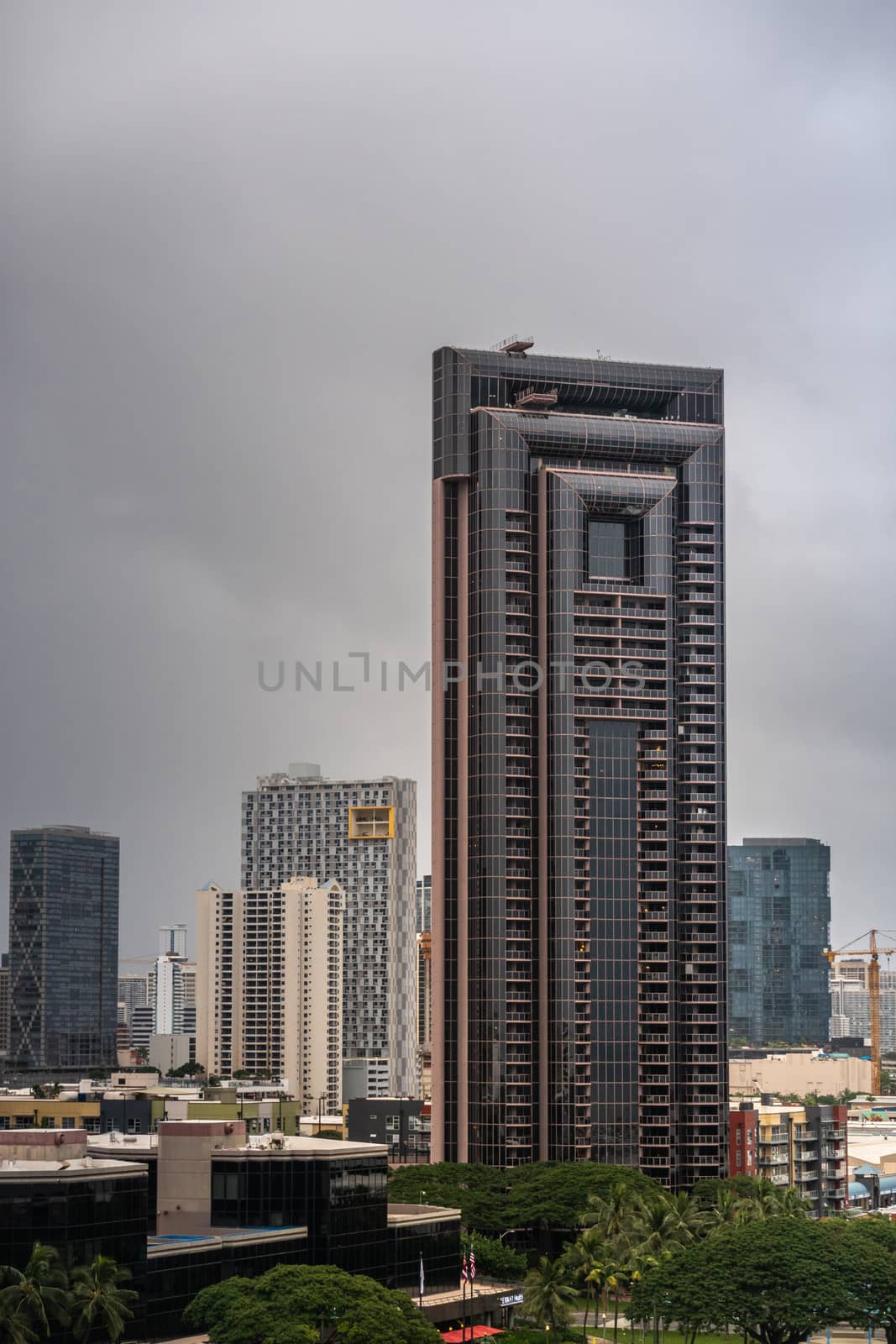 Honolulu  Oahu, Hawaii, USA. - January 11, 2020: One of two identical iconic skyscrapers along South Street near waterfront plaza under dark rainy sky. More buildings in back.
