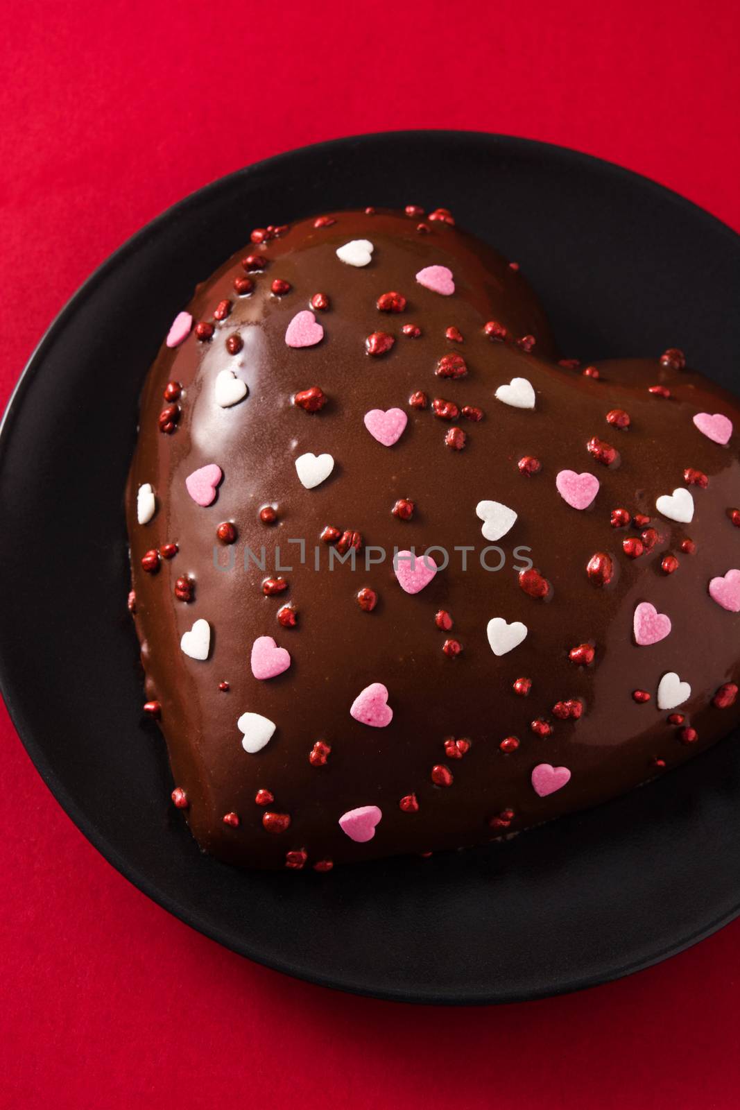 Heart shaped cake and red rose for Valentine's Day or mother's day on red background