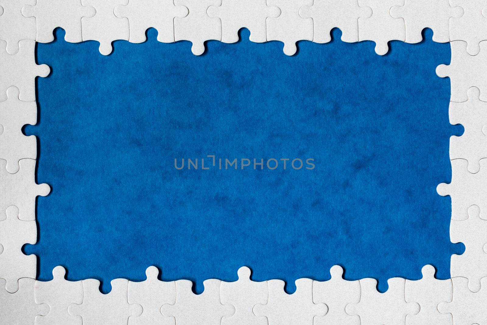 Framing in the form of a rectangle, made of a white jigsaw puzzle. Frame text and jigsaw puzzles. Frame made of jigsaw puzzle pieces on blue background.