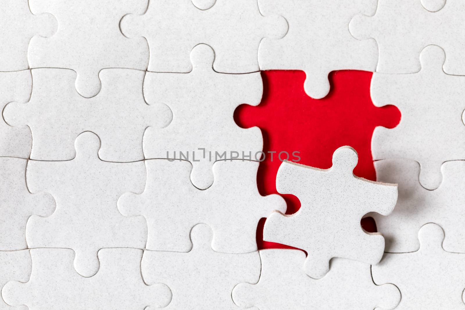 White jigsaw puzzle. White puzzle pieces on color background. Unfinished white jigsaw puzzle pieces on color background. 