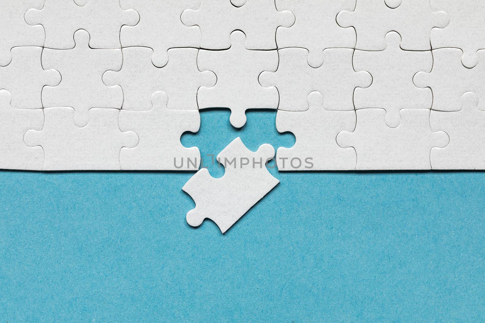 White jigsaw puzzle pieces. Fill in pieces of the jigsaw puzzle. Complete the jigsaw puzzle with the missing pieces. Fragment of a folded white jigsaw puzzle.