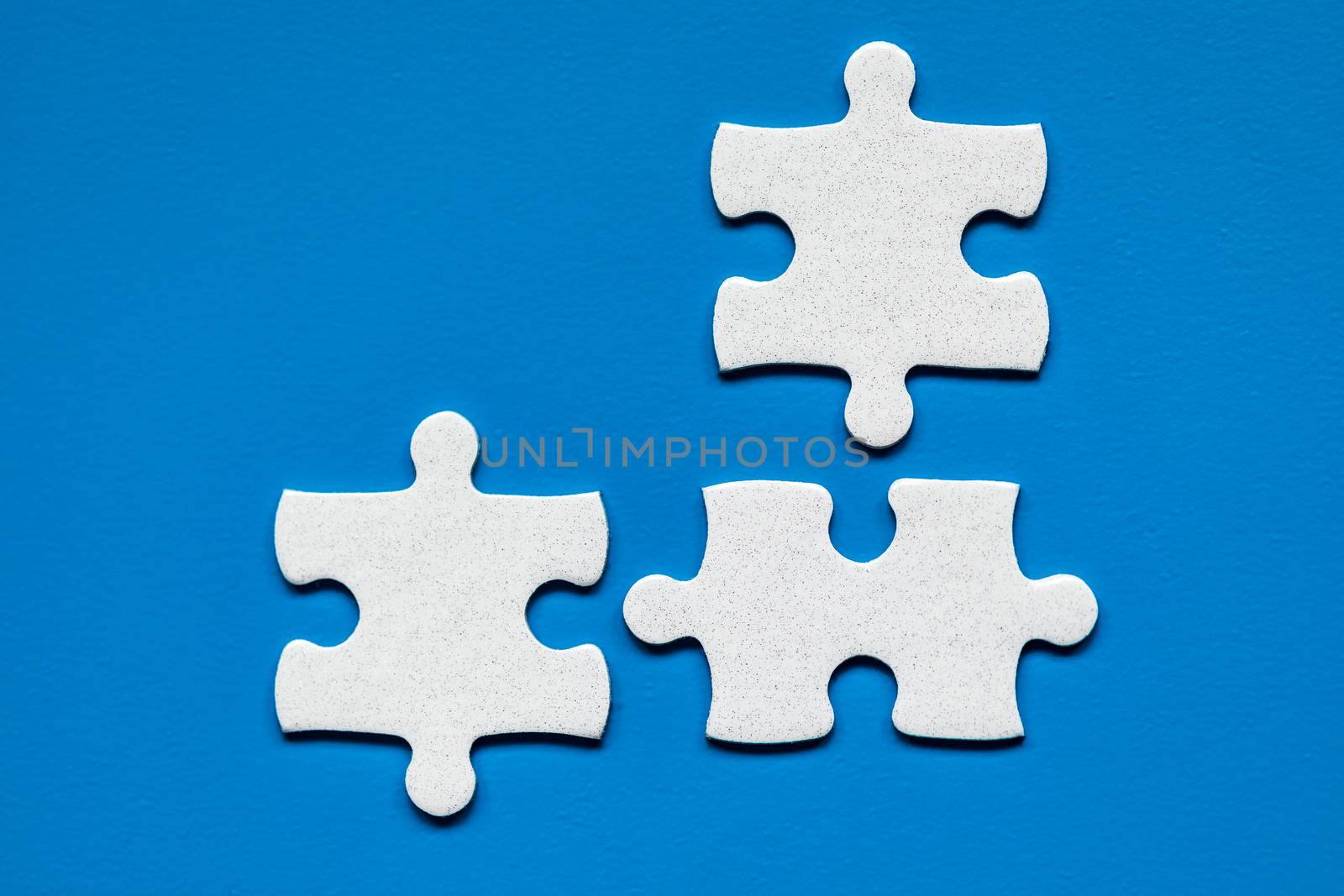 White jigsaw puzzle. White puzzle pieces on color background. Unfinished white jigsaw puzzle pieces on color background. 