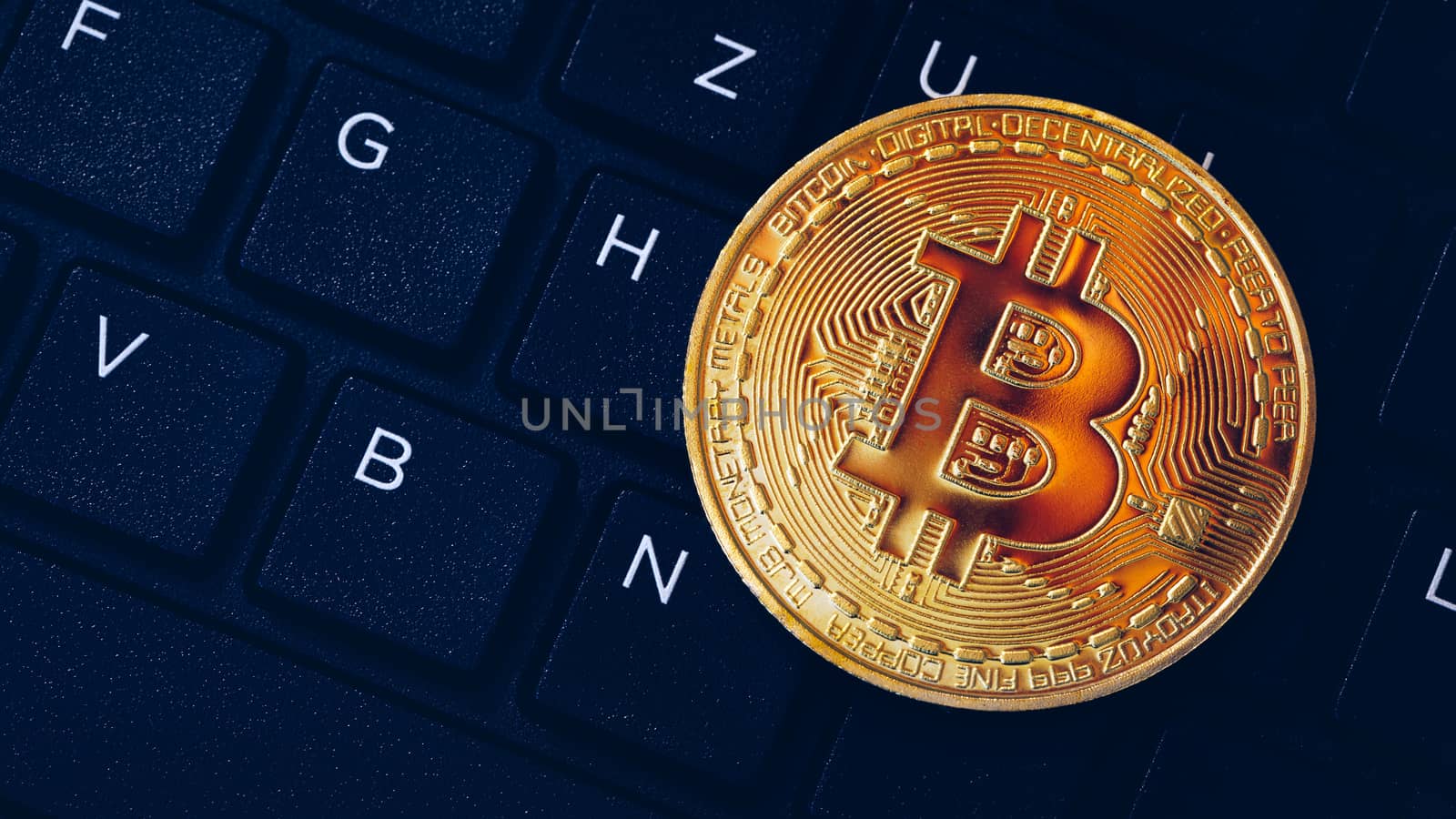 Bitcoin on compuer keyboard in background, symbol of electronic virtual money and mining cryptocurrency concept. Coin crypto currency bitcoin lies on the keyboard. Bitcoin on keyboard.