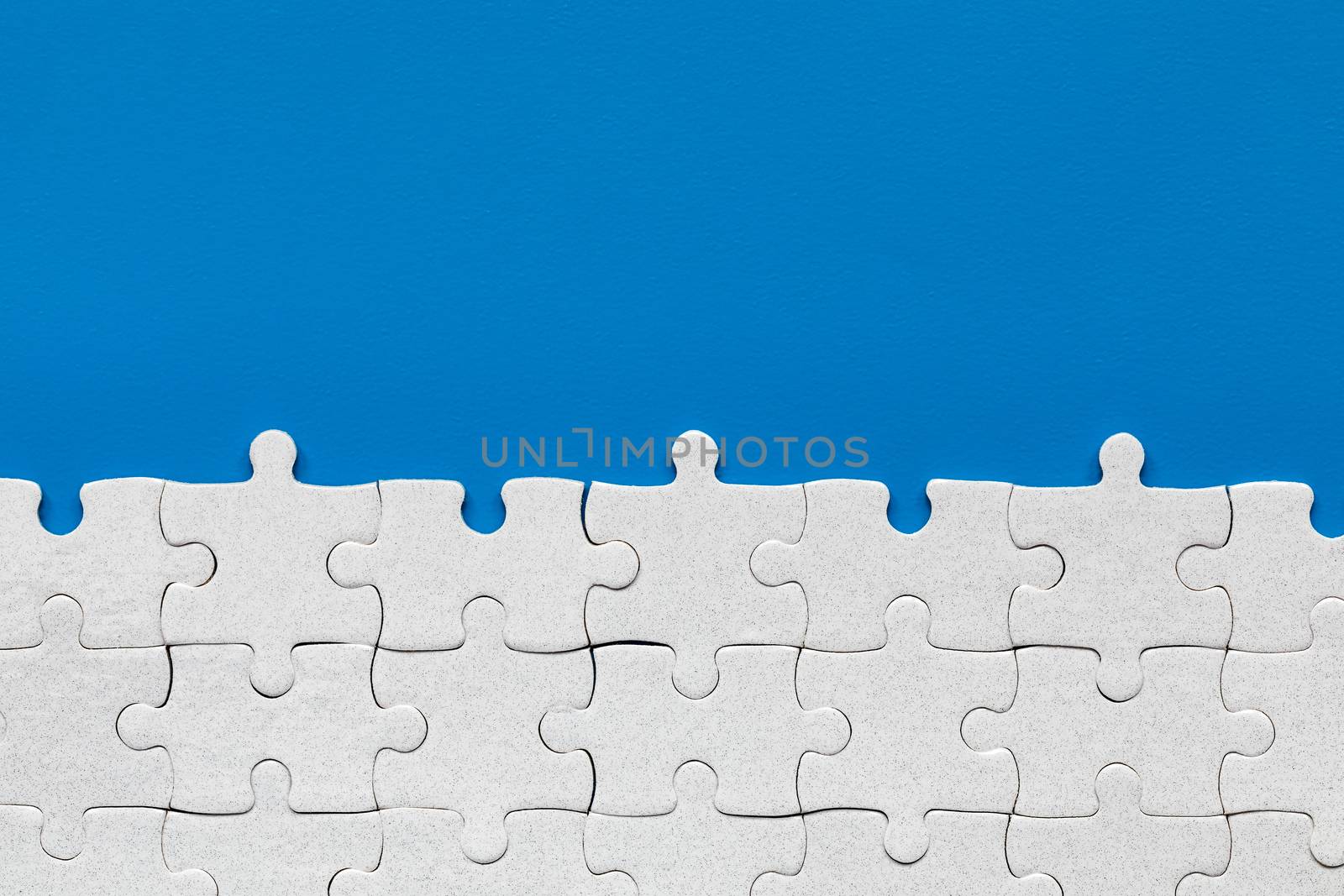 White jigsaw puzzle pieces. Fill in pieces of the jigsaw puzzle. Complete the jigsaw puzzle with the missing pieces. Fragment of a folded white jigsaw puzzle.