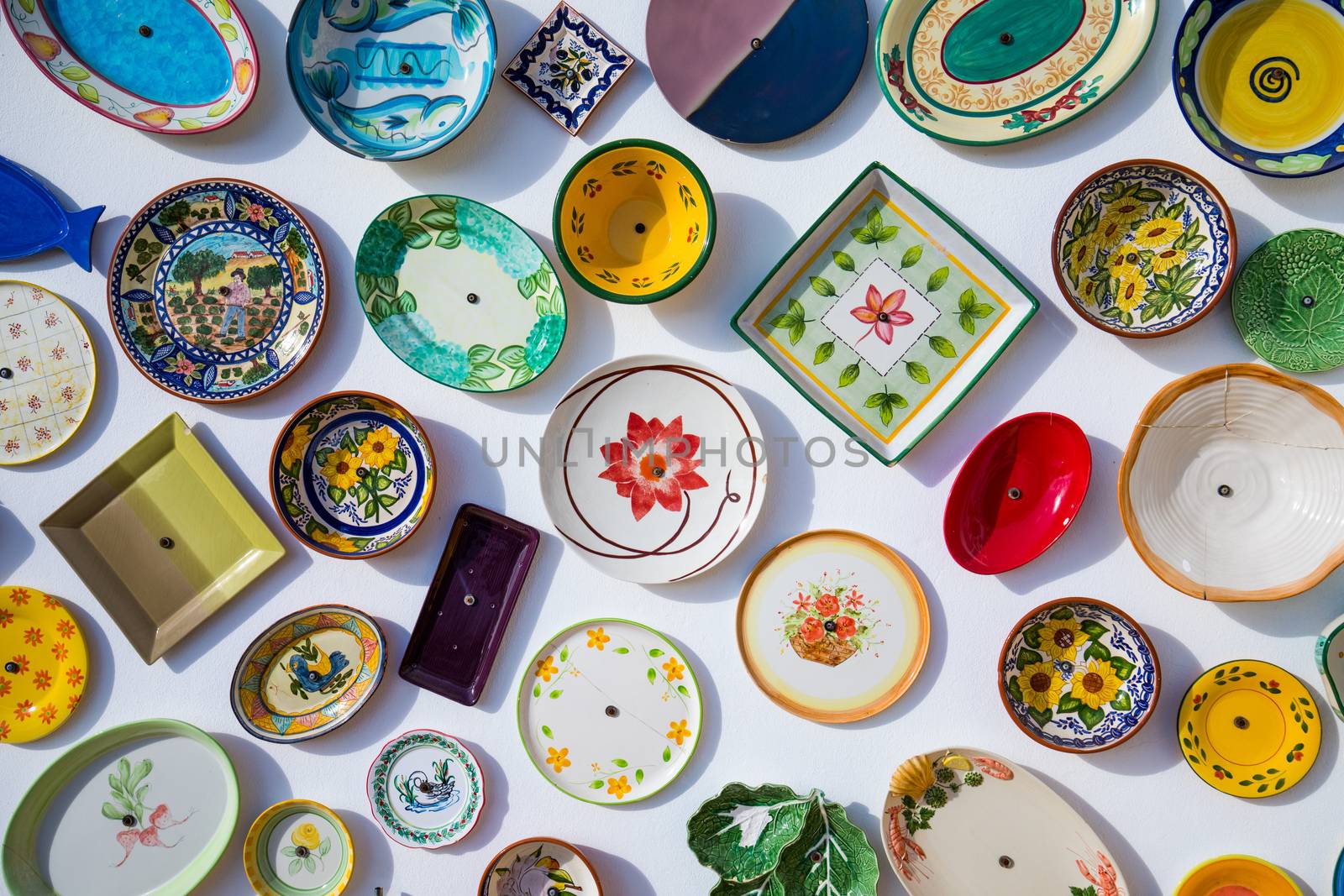 Collection of colorful Portuguese ceramic pottery, local craft products from Portugal. Ceramic plates display in Portugal. Colorful of vintage ceramic plates in Sagres, Portugal.