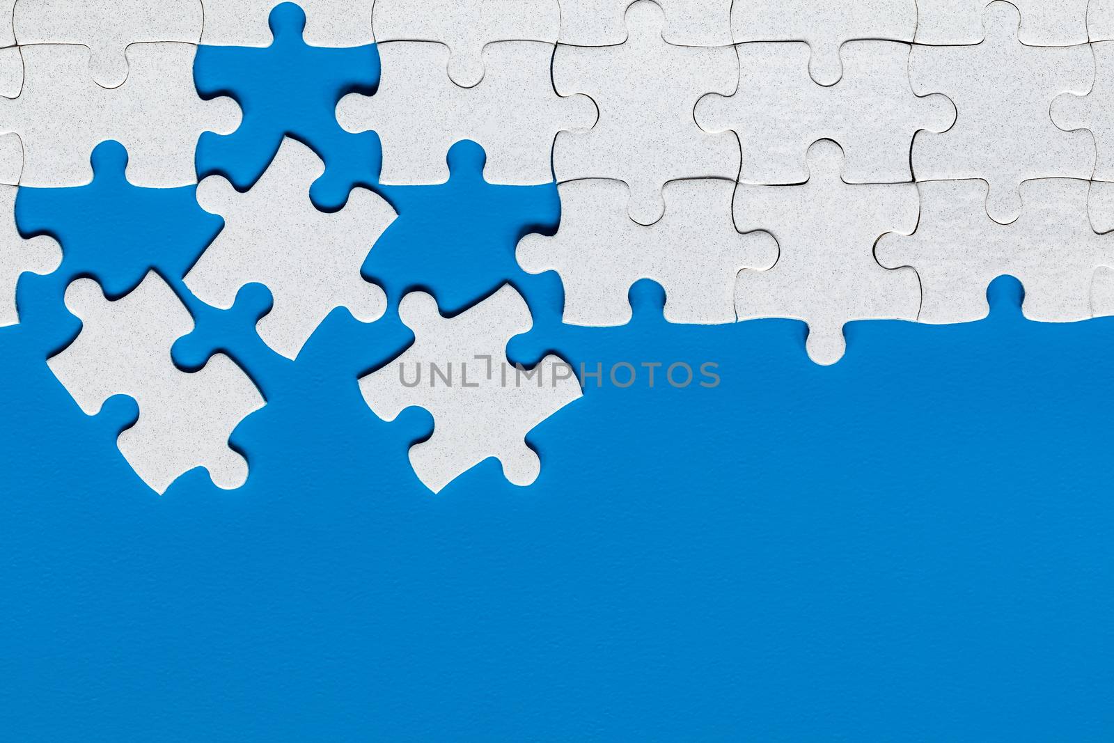 Unfinished white jigsaw puzzle pieces. Fill in pieces of the jigsaw puzzle. Complete the jigsaw puzzle with the missing pieces. Fragment of a folded white jigsaw puzzle.