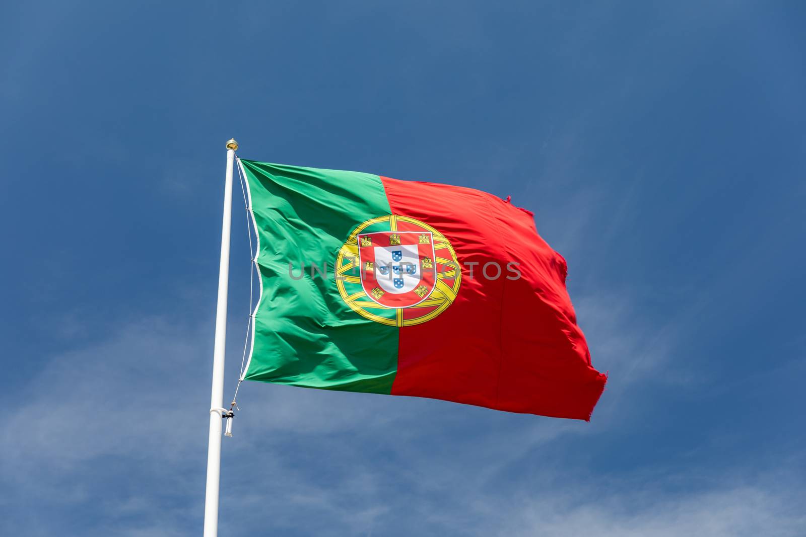 Beautiful large Portuguese flag waving in the wind against blue sky. Portuguese Flag Waving Against Blue Sky. Flag of Portugal waving, against blue sky 