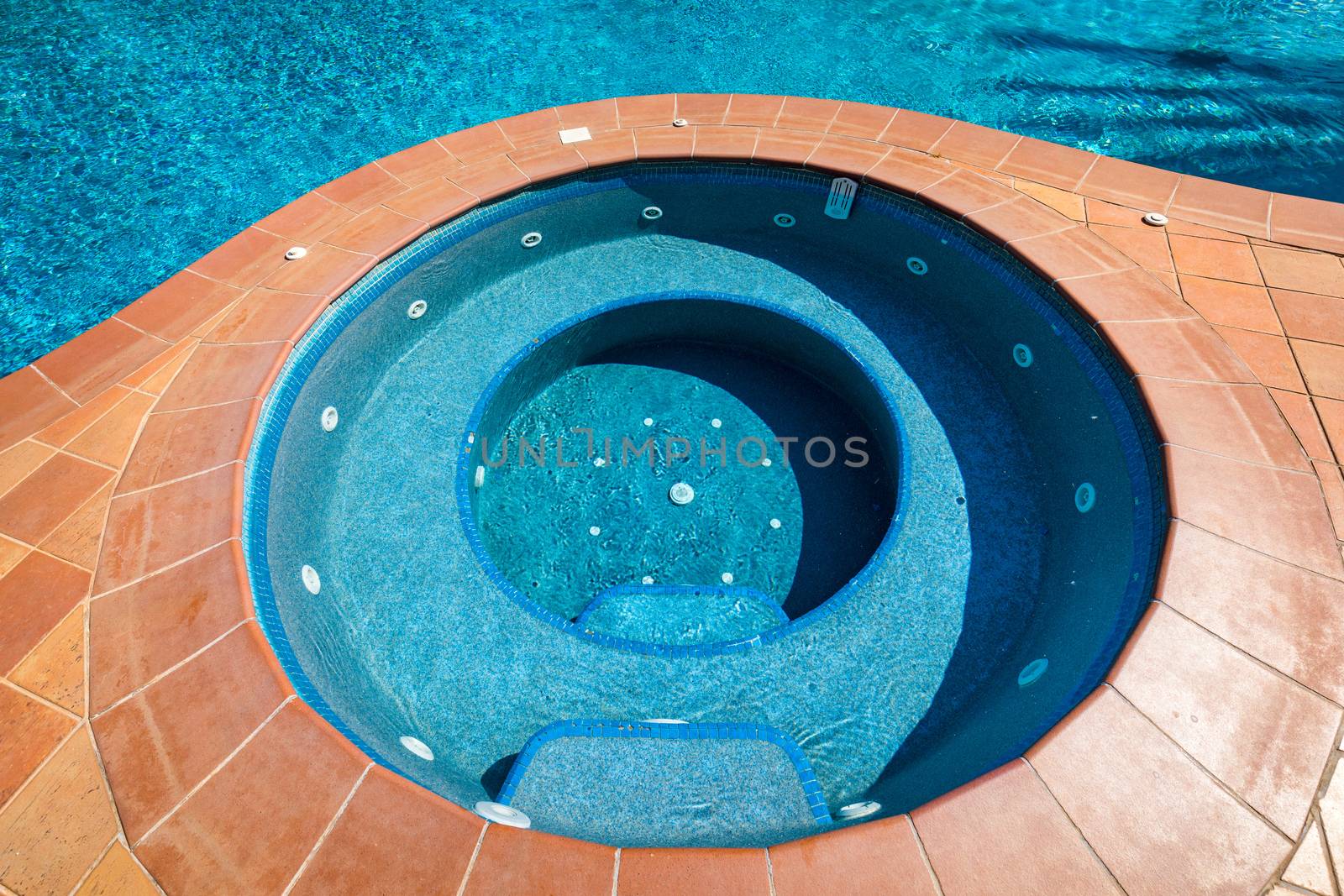 Swimming pool with stair. Grab bars ladder in the blue swimming pool. Poolside with blue clear water and ladder. Stair at the side of swimming pool, summer concept.