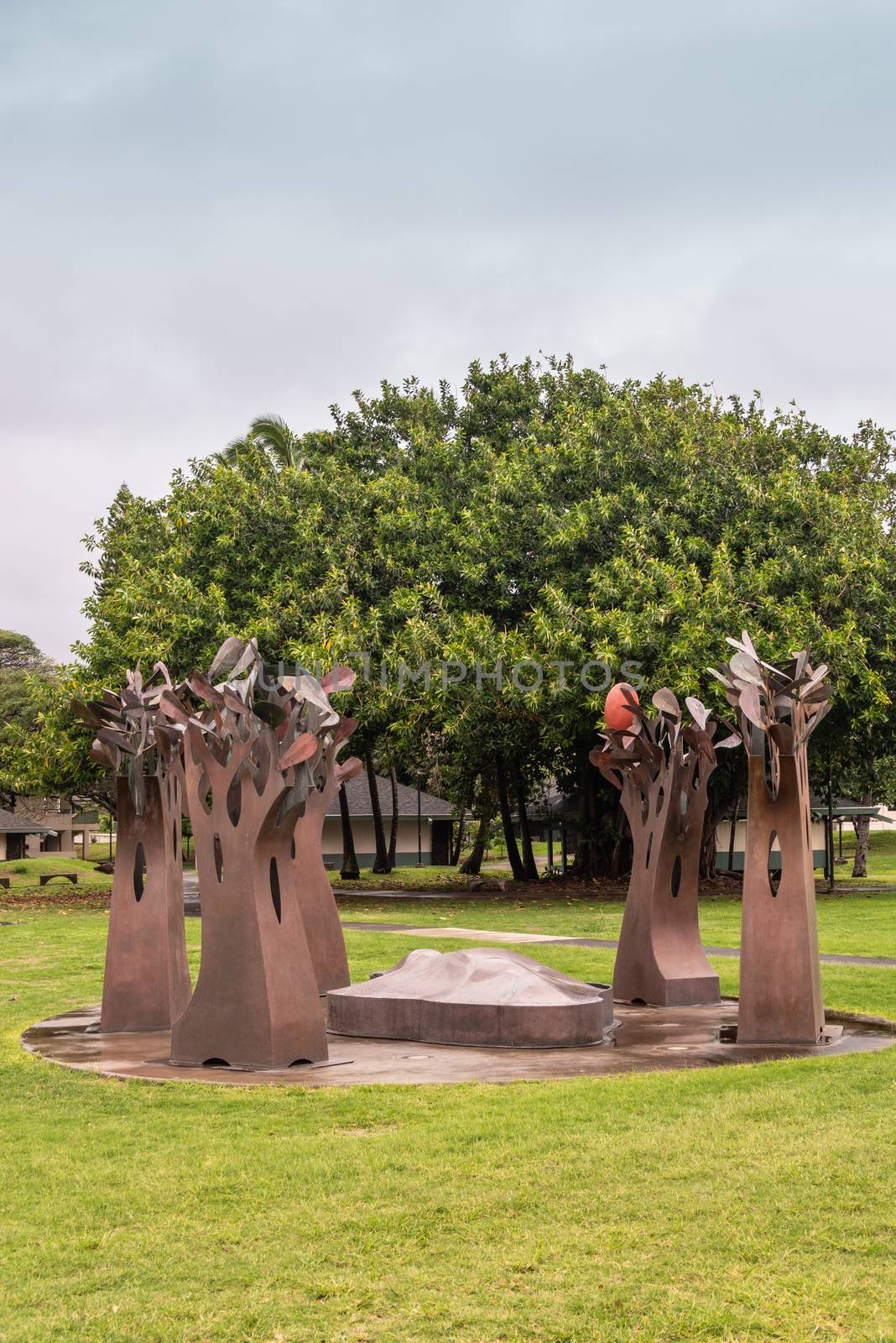 Kahului, Maui,, Hawaii, USA. - January 12, 2020: Portrait of Brown rusty metal group of trees statue on green lawn at University of Hawaii, Maui college campus. Gray cloudy sky. Green foliage in back.