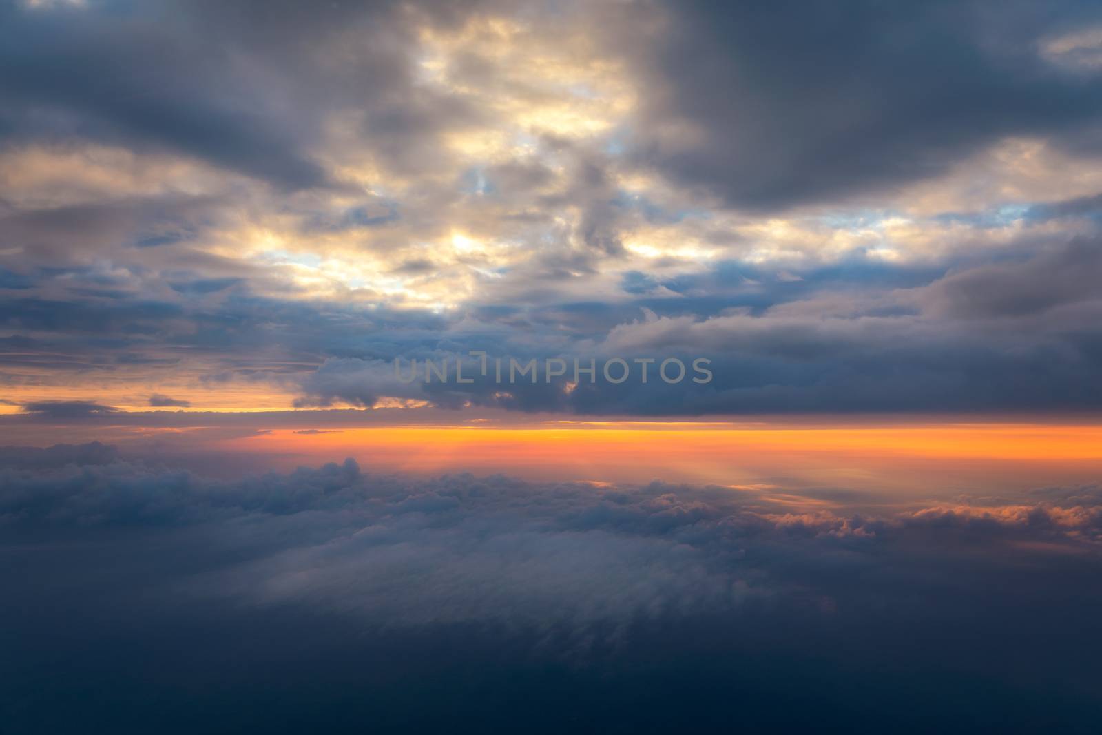 Beautiful sunset sky above clouds with dramatic light. Cabin view from airplane. Flying above the clouds. view from the airplane. Beautiful blue sky background with sunset. Sunset above the clouds.