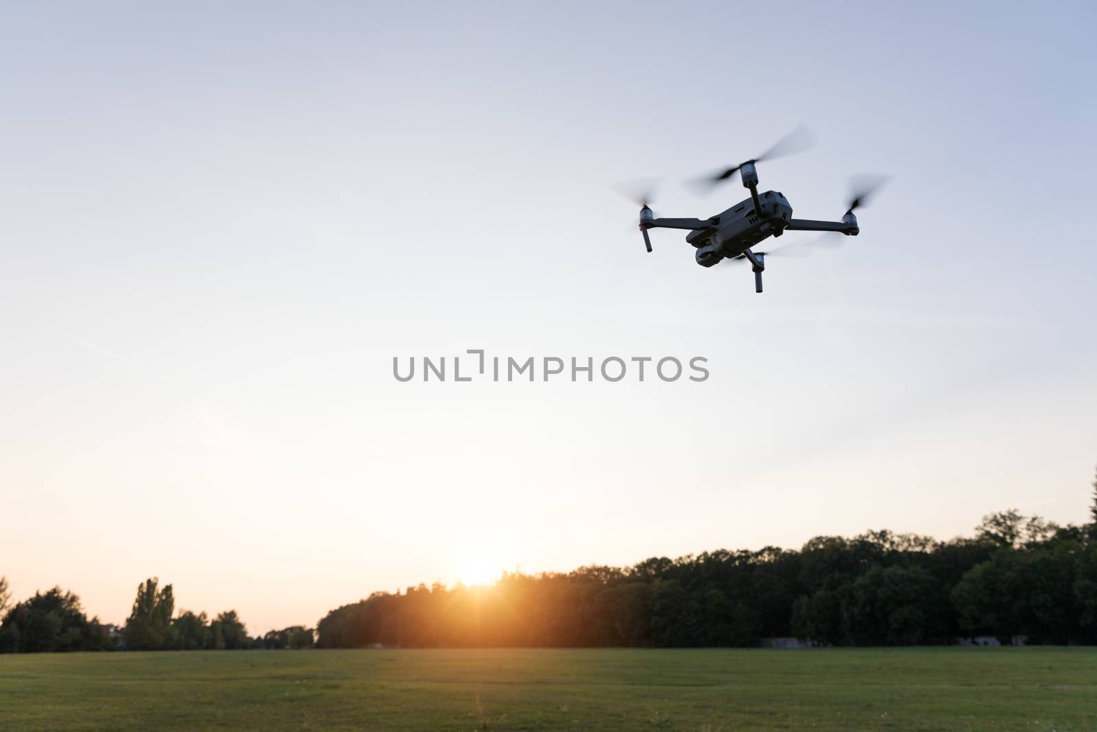 Drone flying over landscape. UAV drone copter flying with digital camera. Drone flying overhead in cloudy blue sky. Quad copter is flying over the  field.