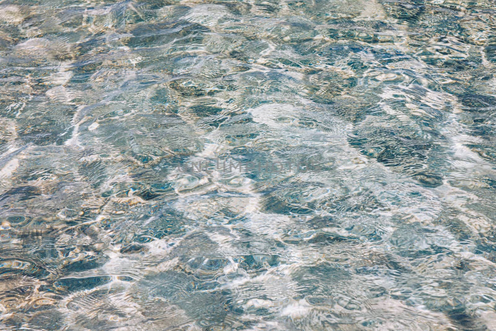 Water surface with bright sun light reflections, sea water background. Water surface with bright sun light reflections. Background of transparent sea water. Blue ripped sea water background.