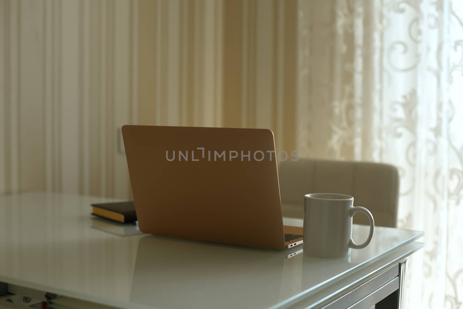 Laptop, diary and a cup of tea on the kitchen's table. Work from home during quarantine