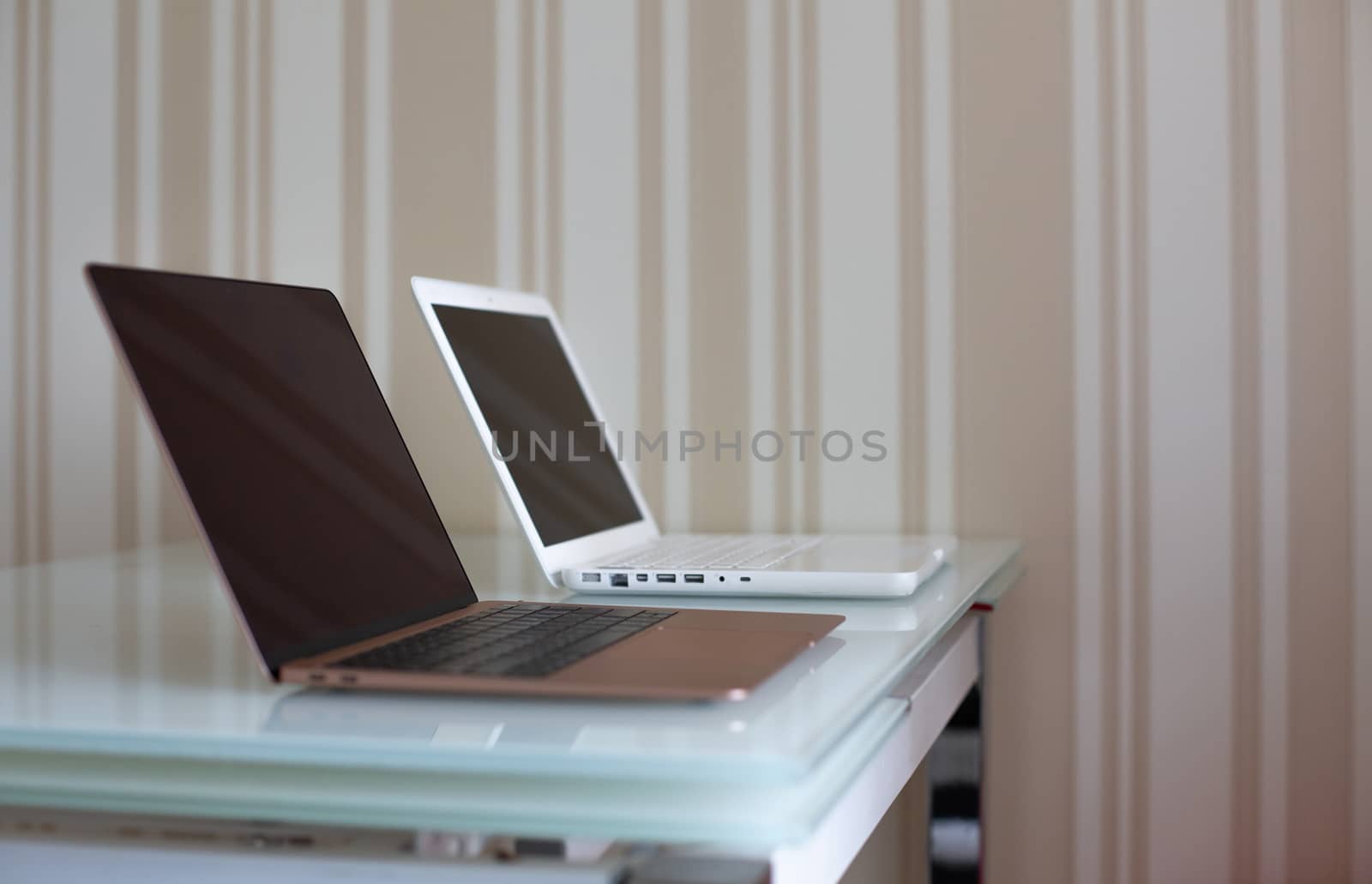 Two laptops on the glass table by ViktoriiaPav