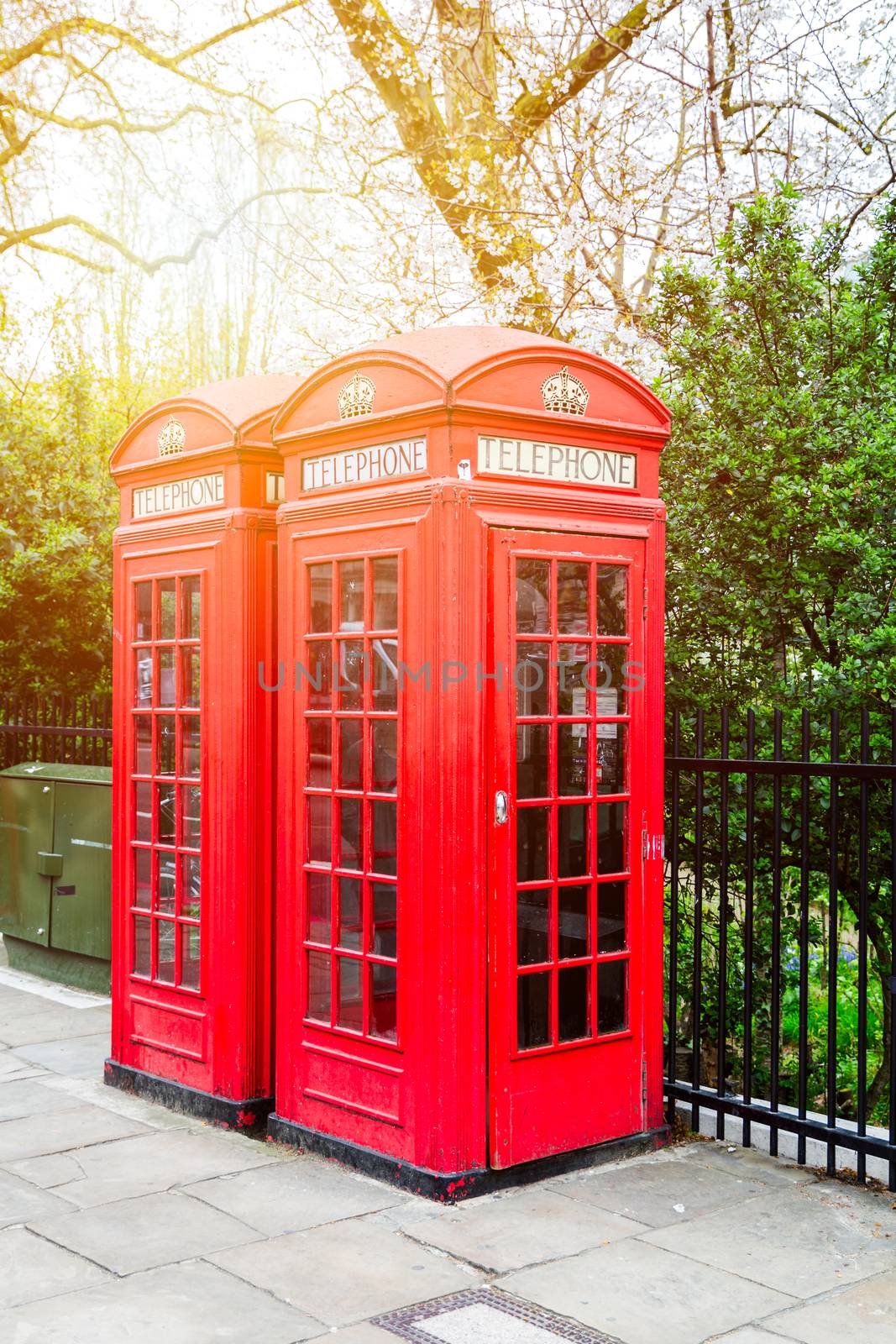 Red telephone box in street with historical architecture in London.