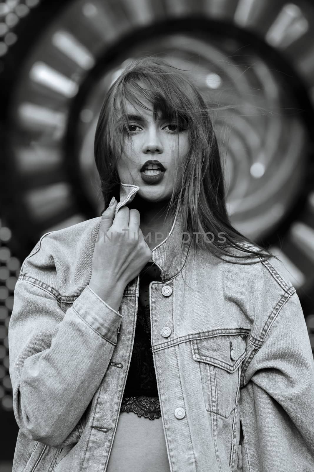 Lifestyle shot of seductive young woman with red lips wears jeans jacket. Monochrome color