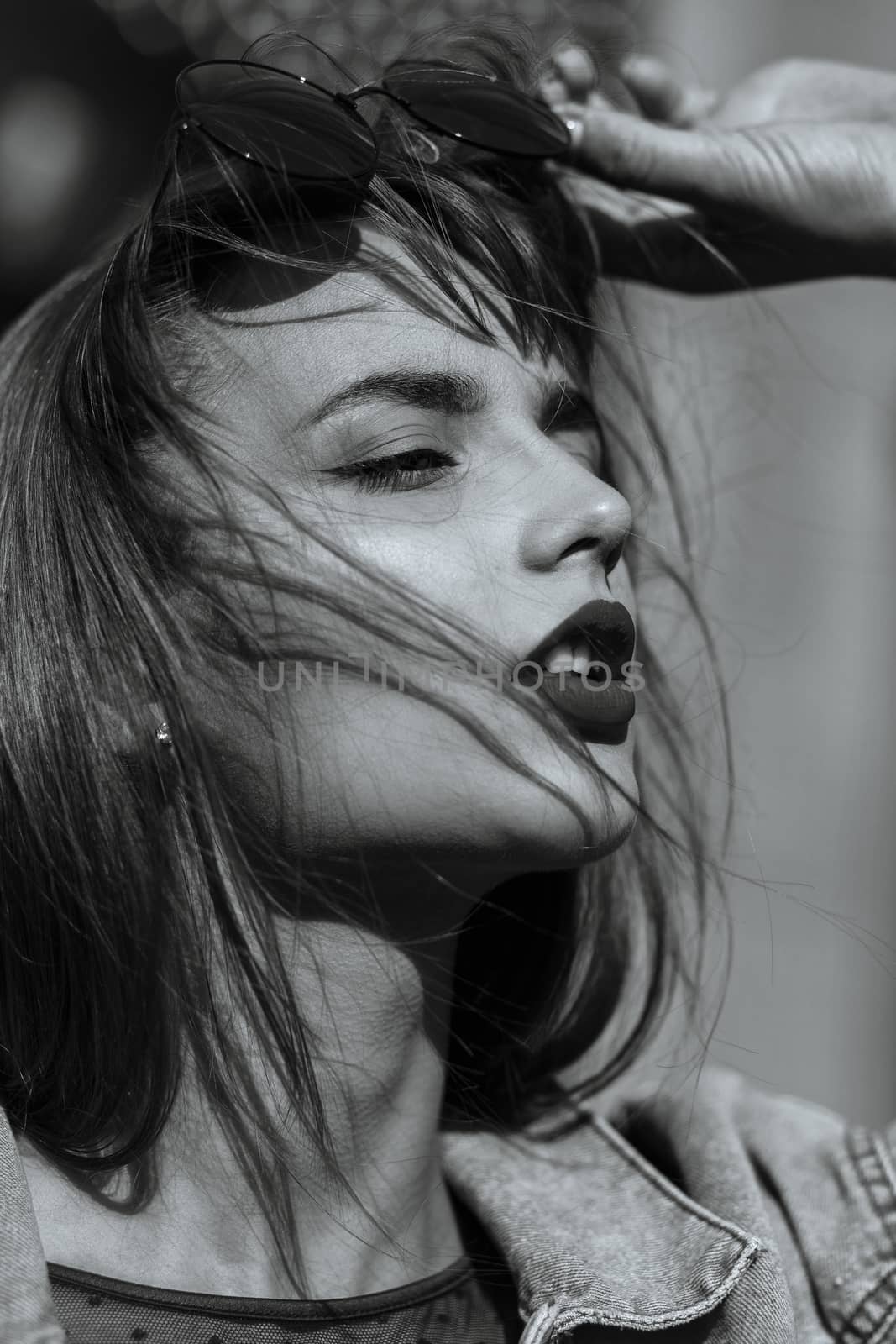 Closeup portrait of magnificent young woman with red lips wears jeans jacket. Monochrome color